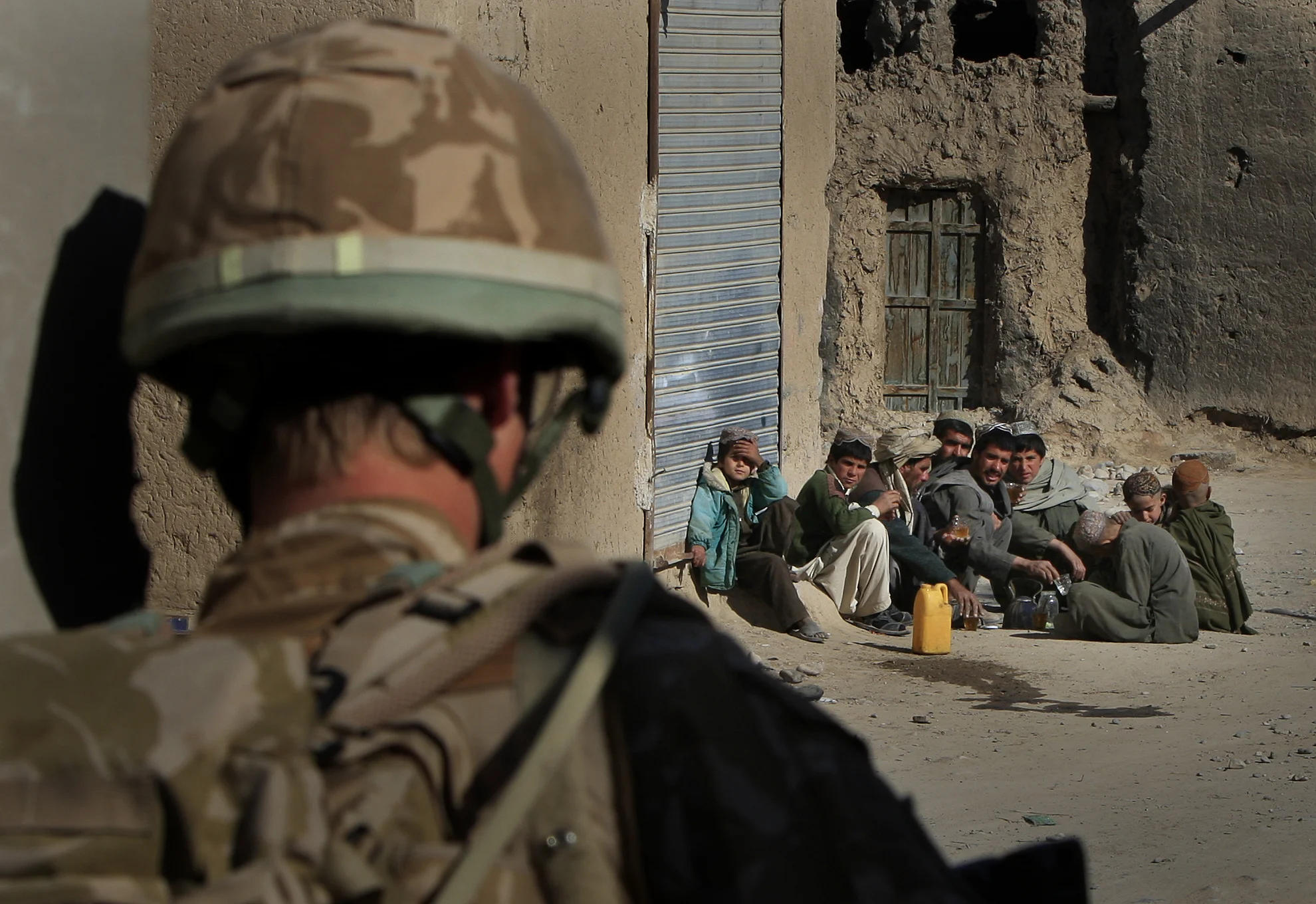  A British Soldier of 3 Rifles watches over a group of young Afghan men in Sangin, Afghanistan, 2010. 