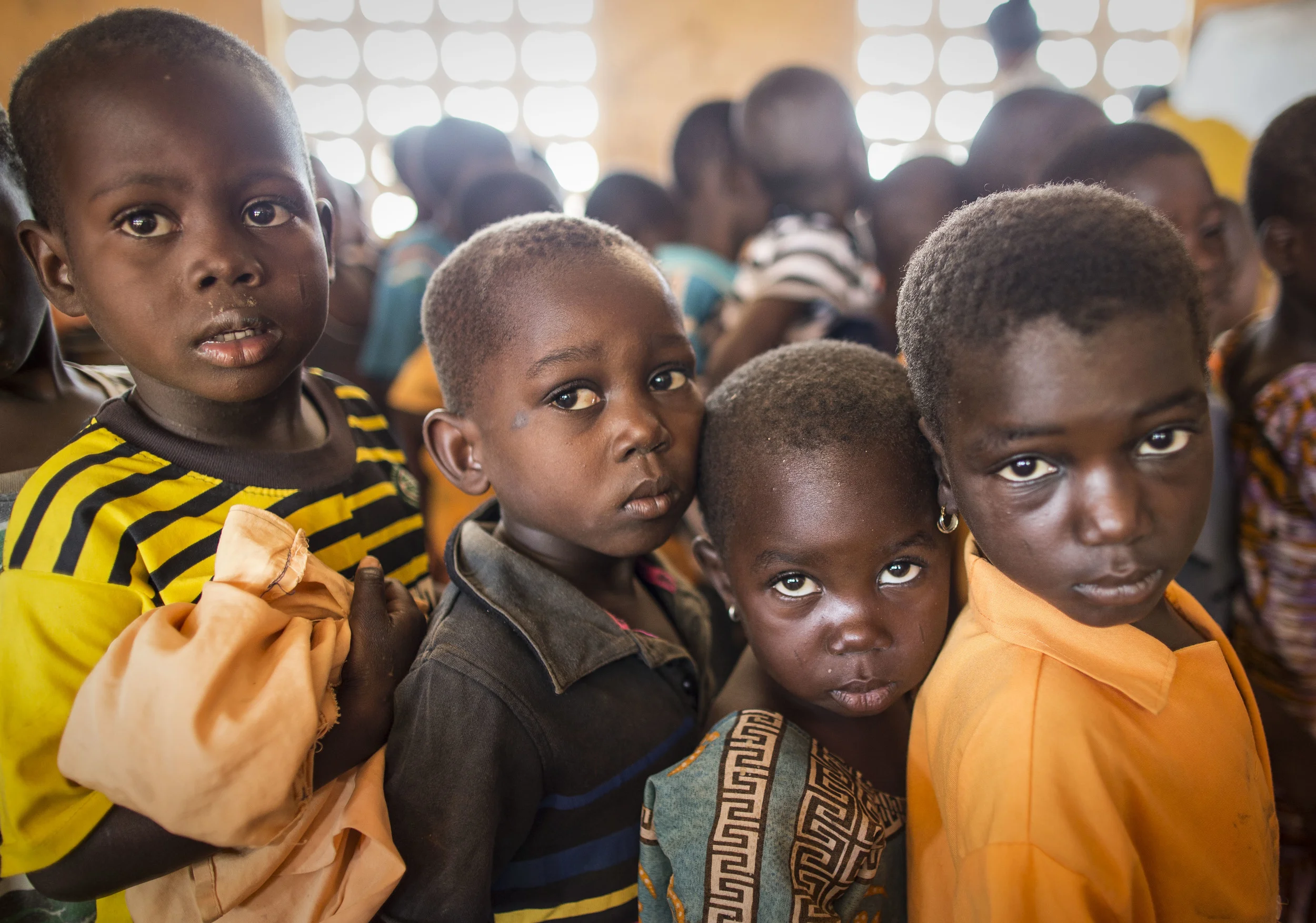 Children at Zaari village school queue to have their eyes inspected by Opthalmic nurse, Iddrisu Abdulai. 'Sightsavers' and the Ghanaian health service work closely together to combat trachoma. November 2013.