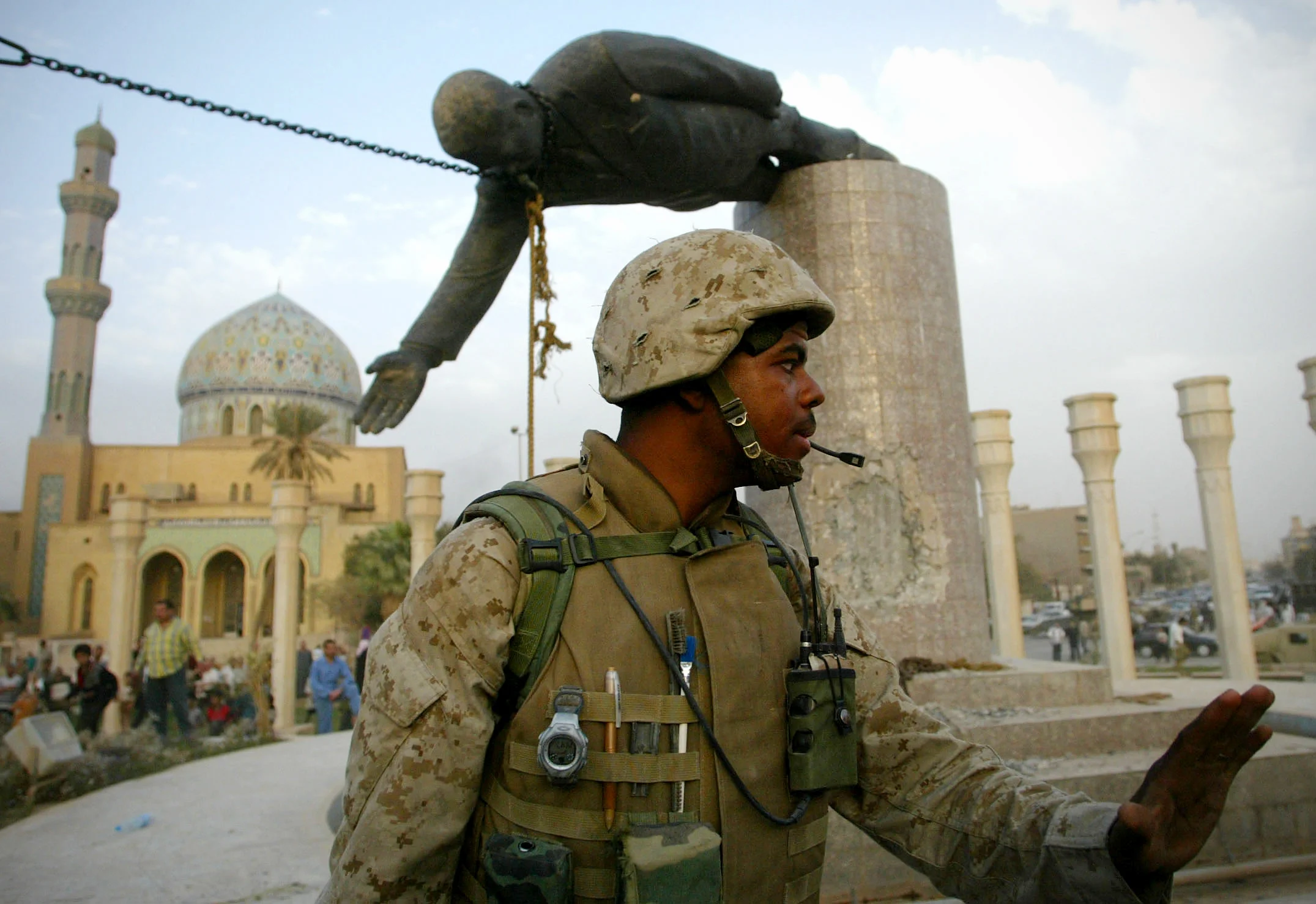 As U.S military engineers pull down a statue of Saddam Hussein in central Baghdad, a soldier keeps back a crowd also waiting to destroy the icon of the deposed ousted Iraqi leader. Baghdad, April 9, 2003.