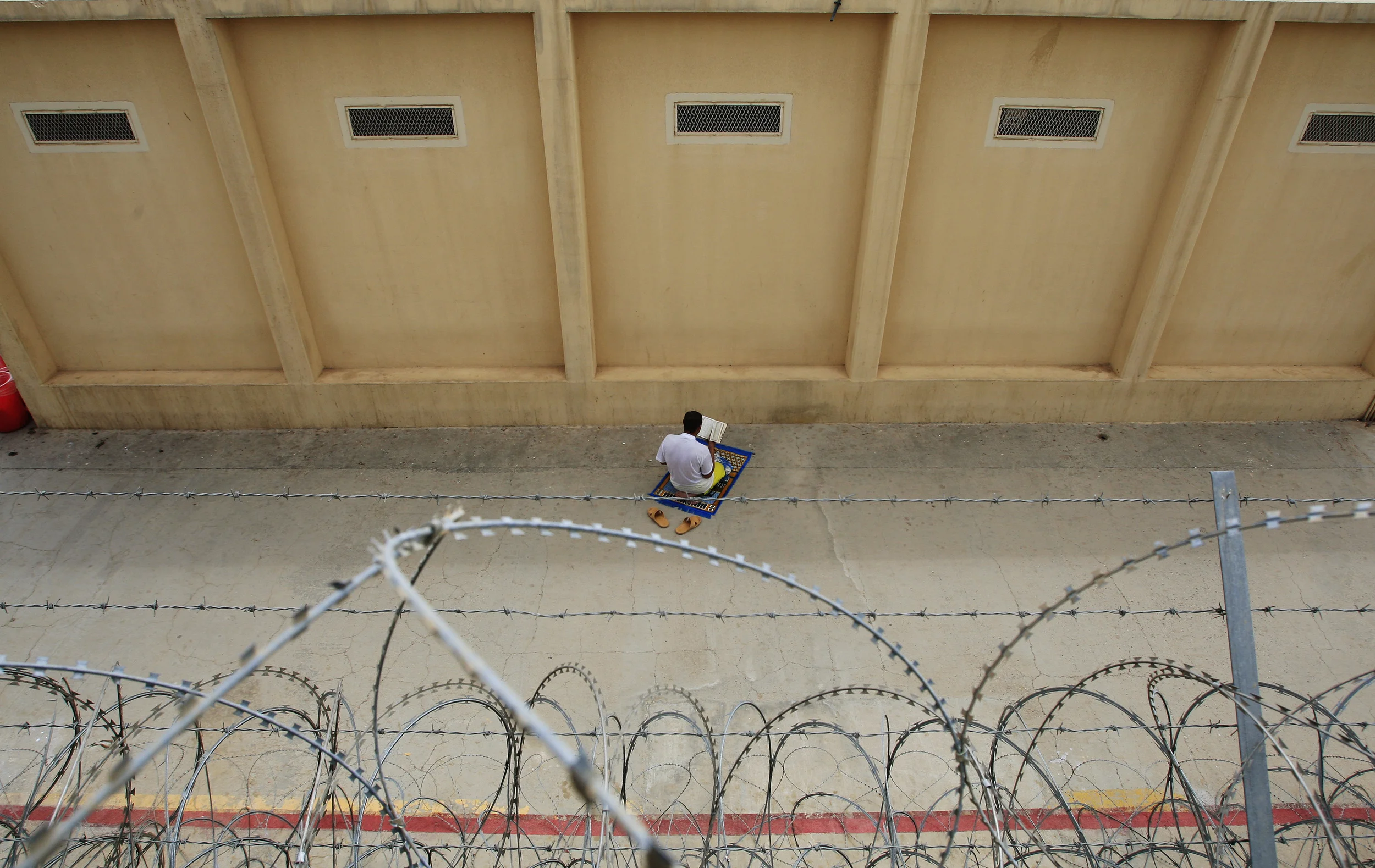 Behind a secure perimeter fence, an Iraqi detainee at the U.S. run prison, Camp Cropper, prays alone. Baghdad, April 2009.