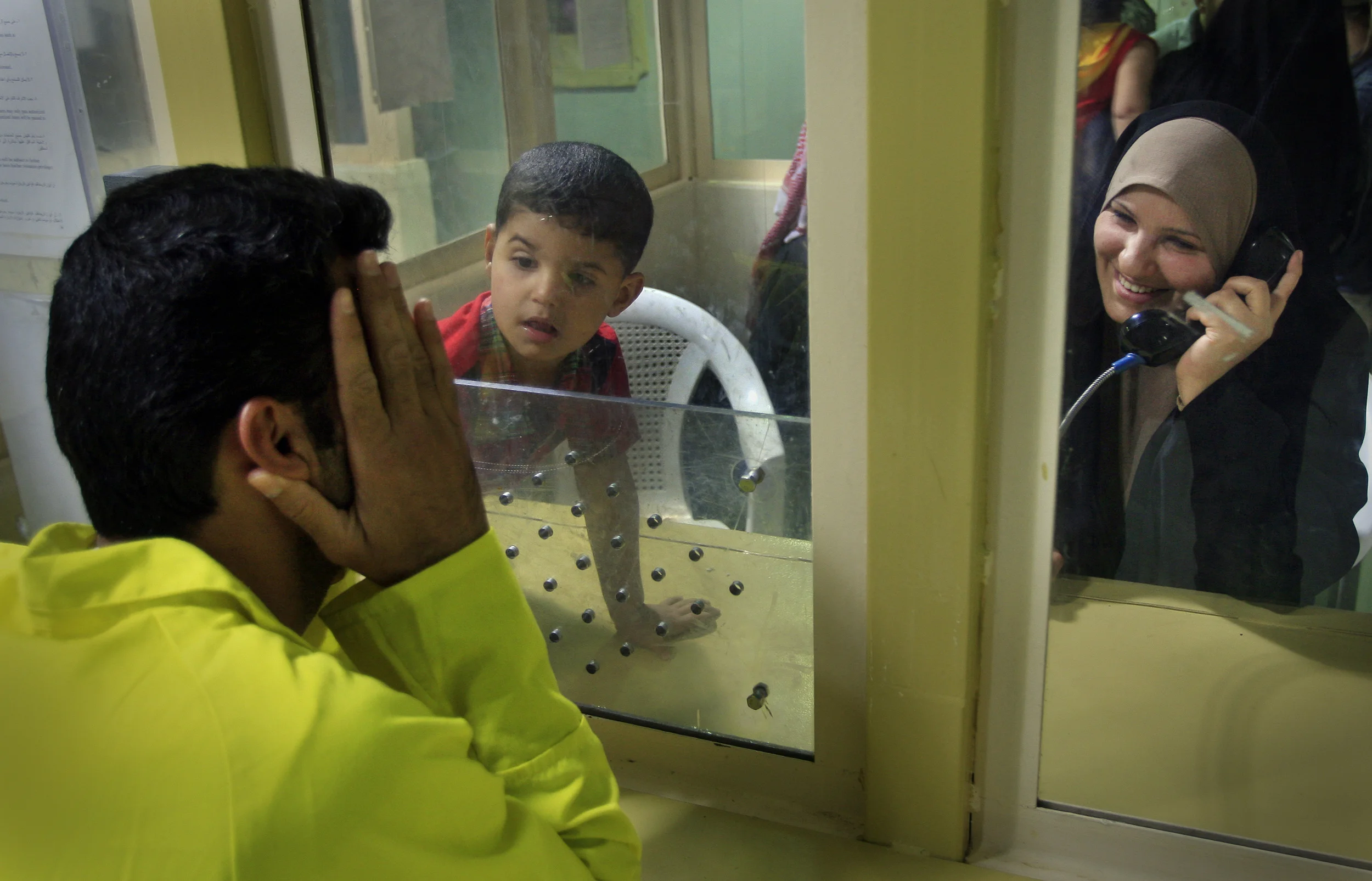 Iraqi detainees at the U.S. run prison, Camp Cropper, are allowed family visits and may have private conversations through toughened glass and via a telephone. (Identities concealed as they are suspects only at this point, not convicts). Baghdad, April 2009.