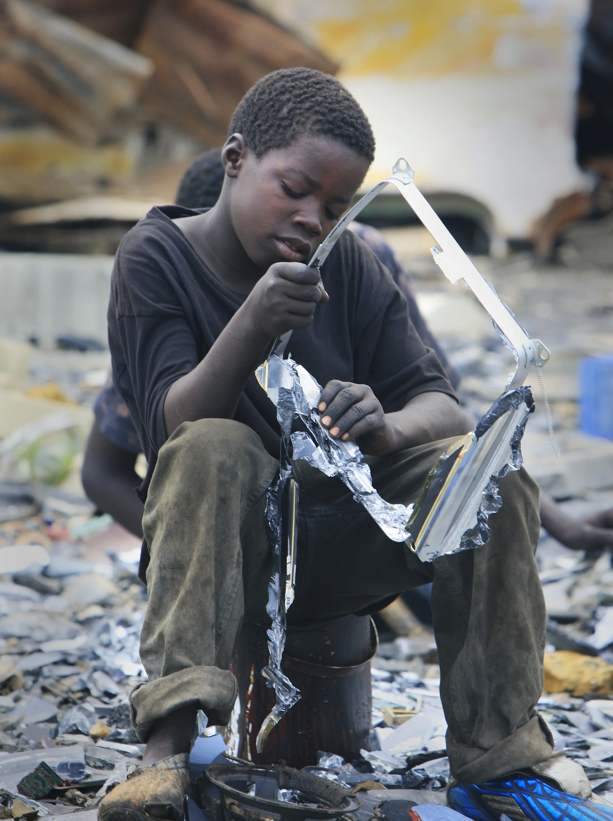 A young boy working with omputer salvagers at Agbogbloshie in Accra, Ghana, re-cycle the components of computers dumped from Europe and the West, with catastrophic environmental consequences. July 2009.