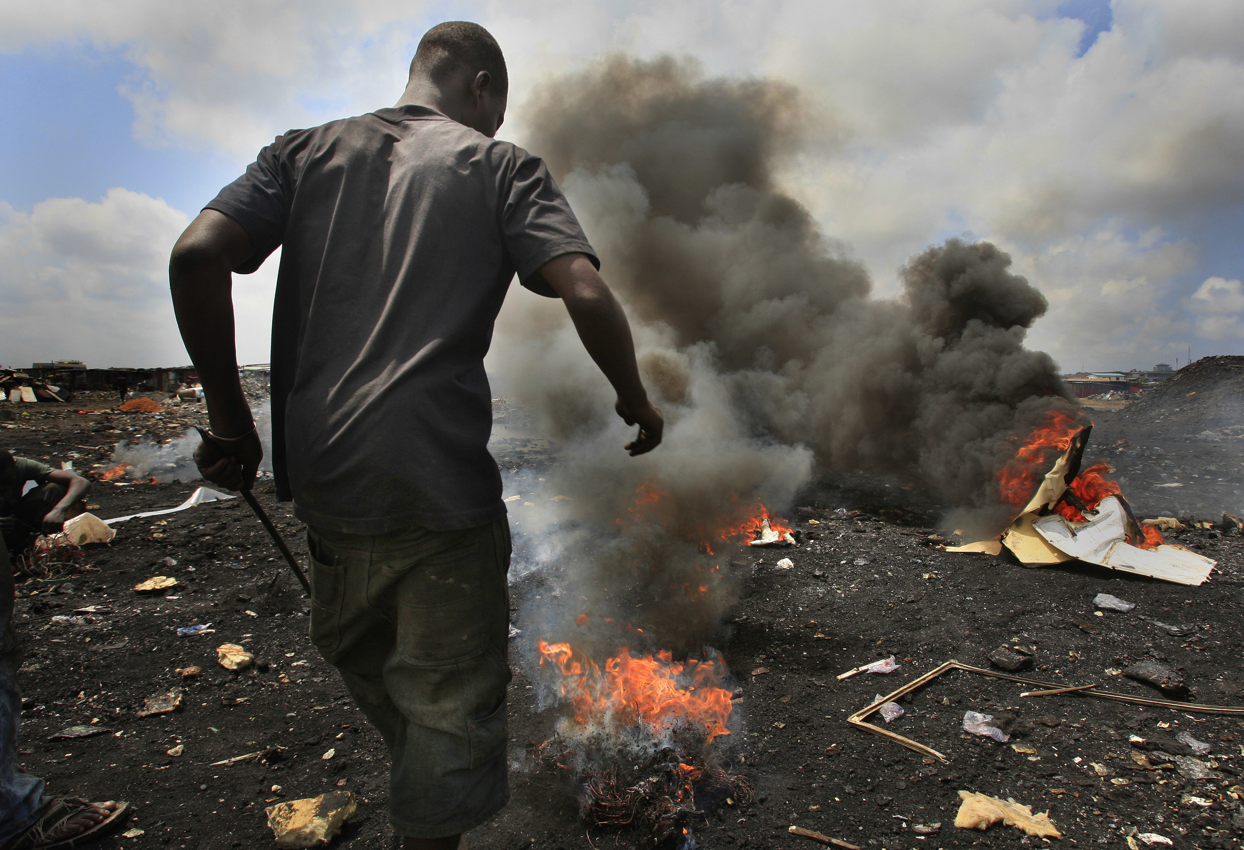 A young man burns the plastic off copper cabling at Agbogbloshie in Accra, Ghana, where the components of computers are re-cycled with catastrophic environmental consequences. July 2009.