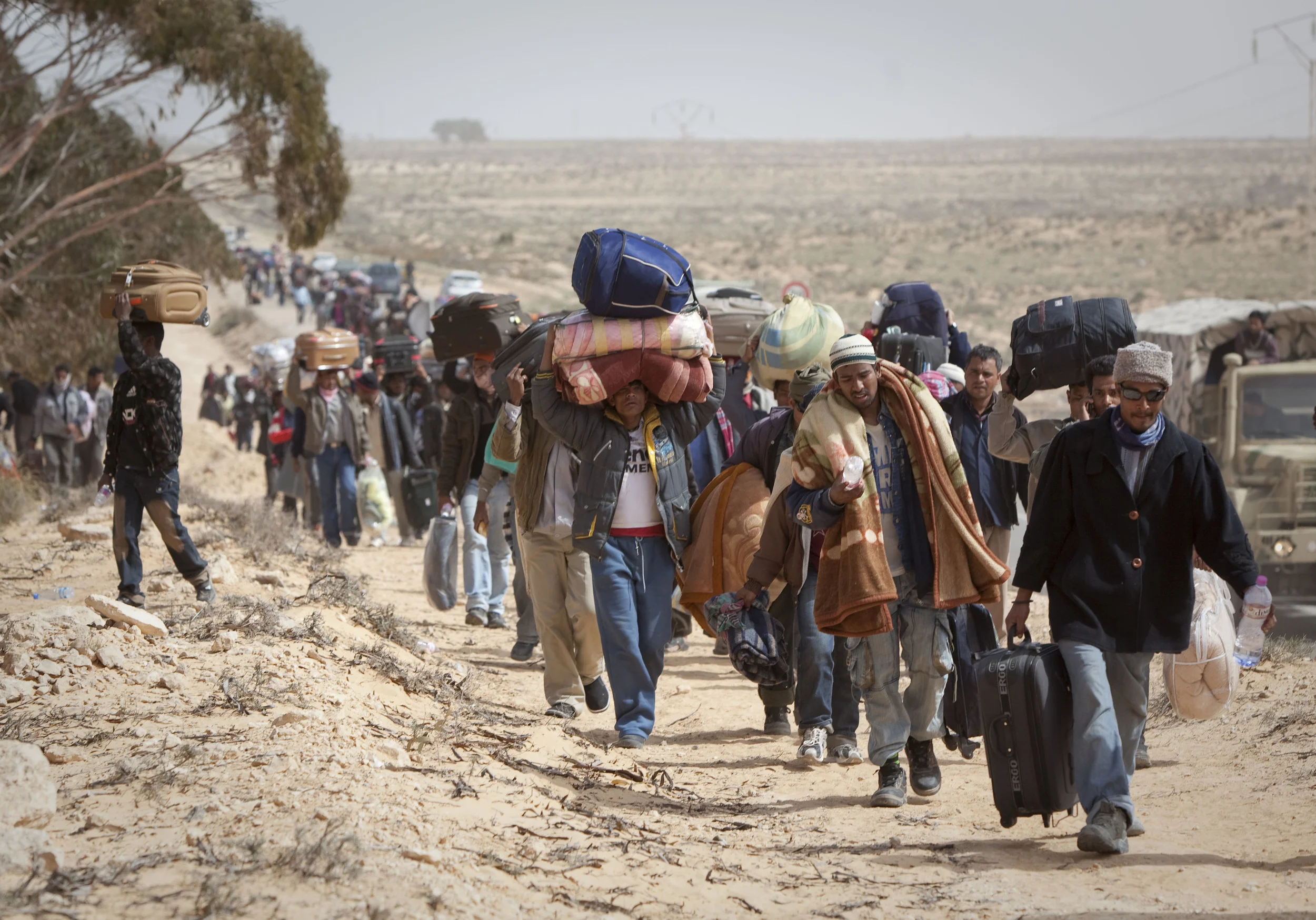  Some of the thousands of Bangladeshi refugees stream further into Tunisia from the border with Libya, at Ras Jdir, toward a transit camp. March 2011.    