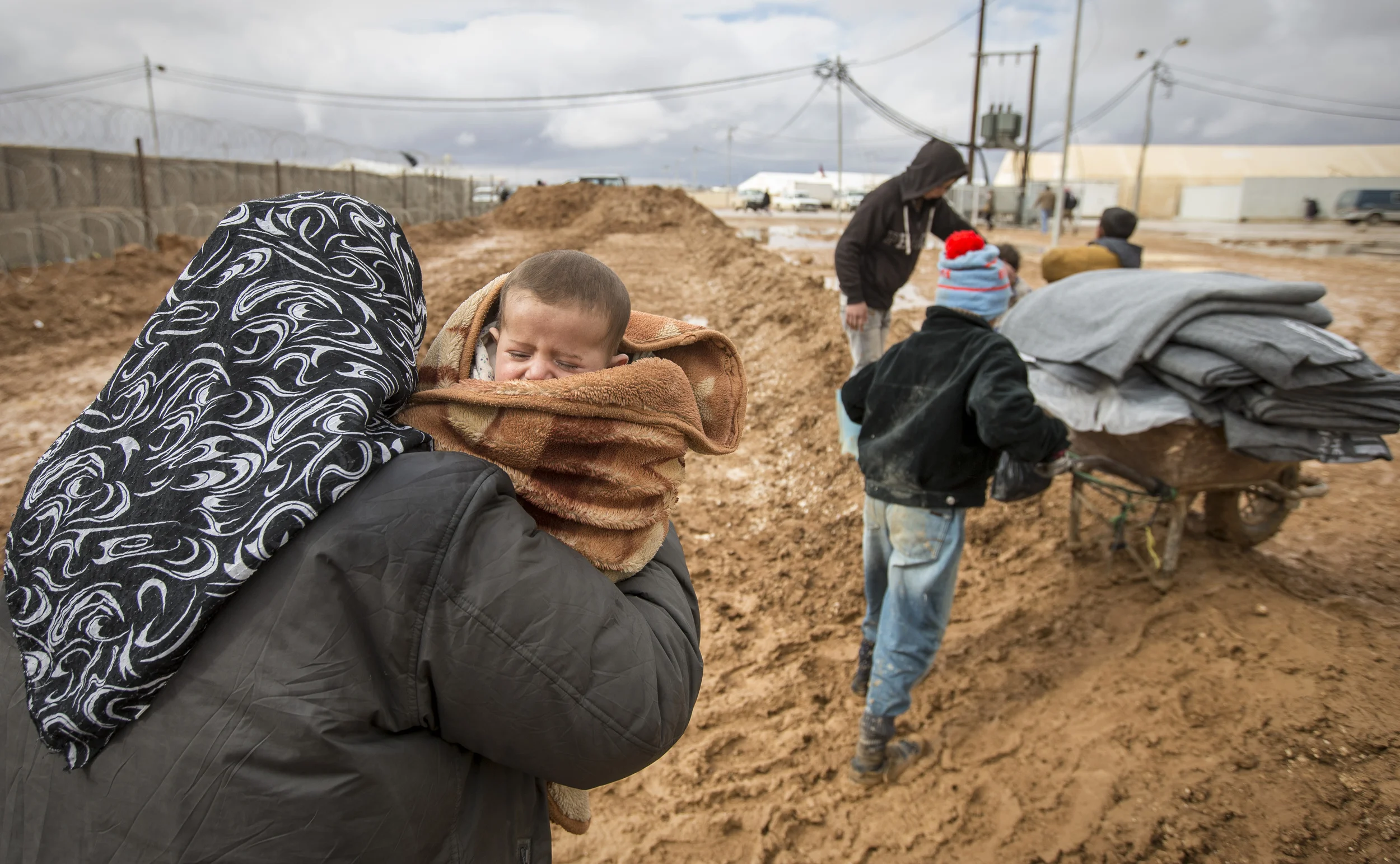 A woman struggles with her baby in the mud of the Za'atari refugee camp in Jordan where over 80,000 Syrian refugees are sheltering from the civil war and winter conditions. December 2013.