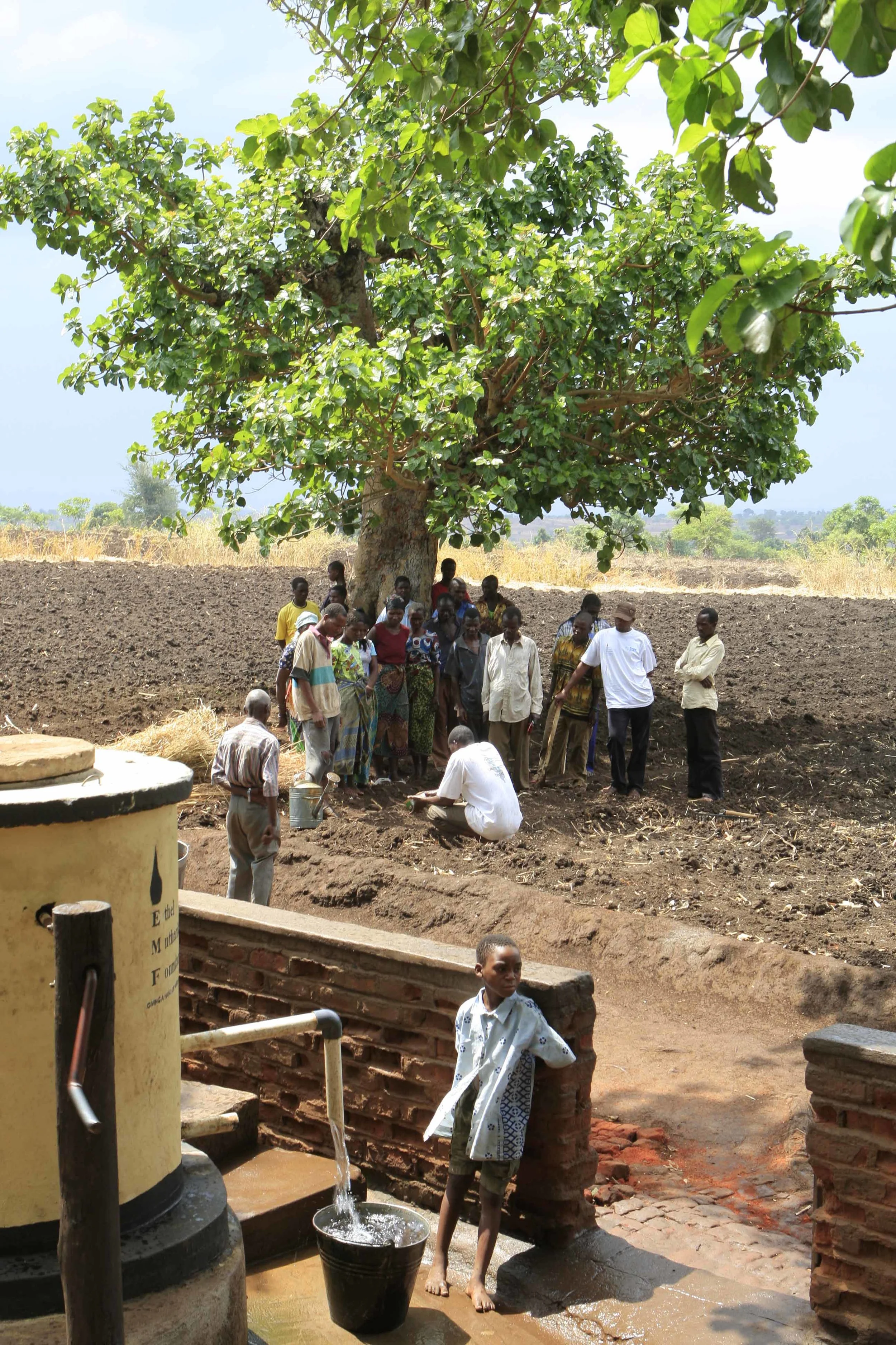  Maxwell Kasinja Kakunga (crouching) of Pump Aid, Malawi, talks to villagers in Mwachilolo on how to plants seeds in a vegetable garden situated next to the 'Pump Aid' Elephant pump, providing fresh water for the village. November 2008. 