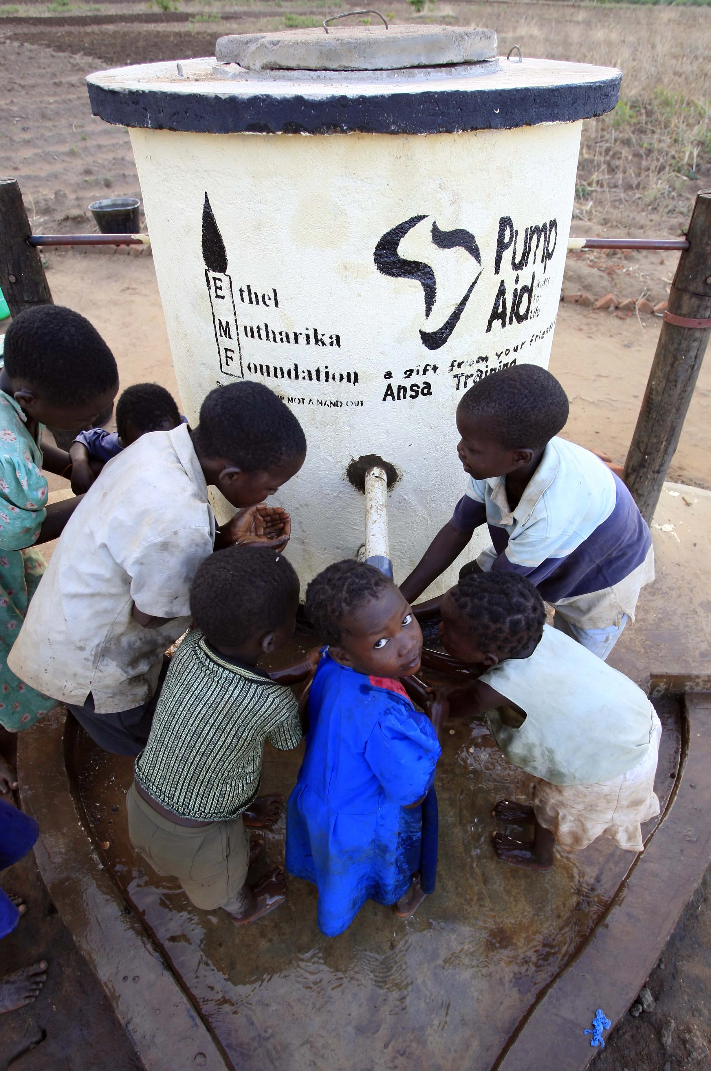  Children from the Malawi village of Kaloumba drink water from the spout of a 'Pump Aid' Elephant water pump. November 2008. 