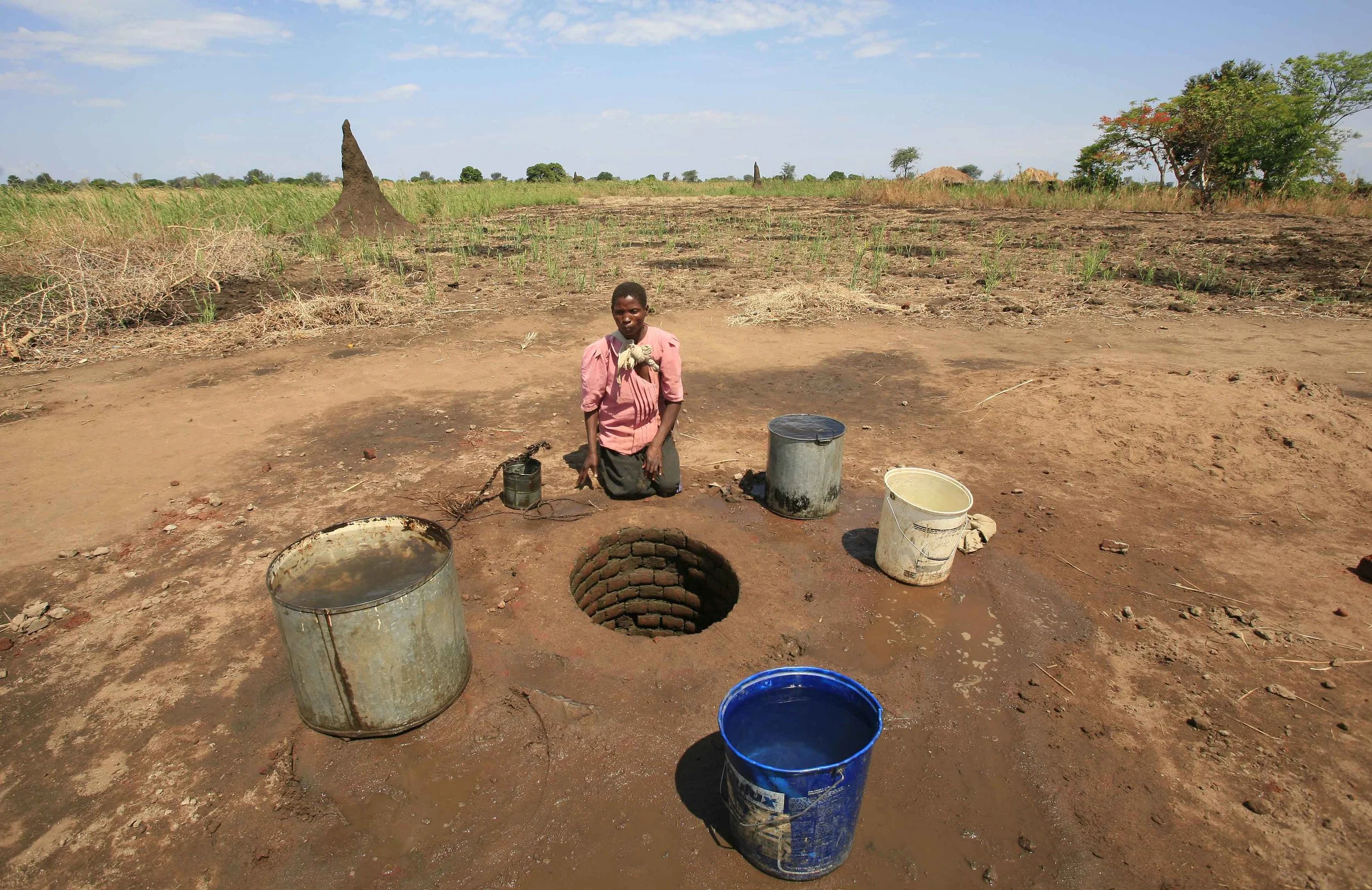  Eznat Nzoza, mother of four, takes water from a decaying well in the village of Paulo, Malawi. 'Pump Aid' replaced it with an Elephant pump. &nbsp;November 2008. 