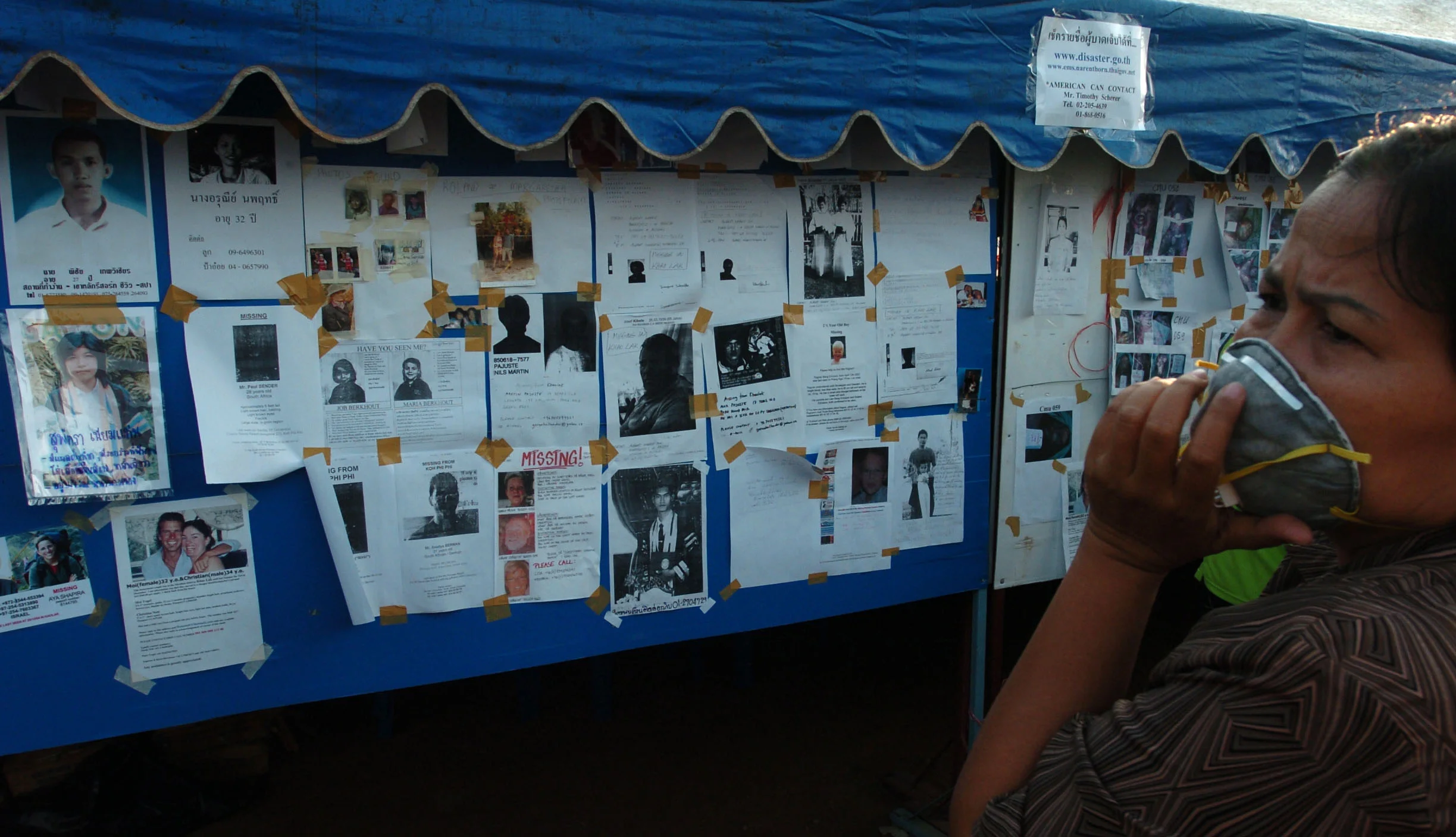  Following the Asian tsunami of Christmas 2004, people seek information of missing loved ones and friends posted on an information wall in Phuket, Thailand. January 2005.&nbsp; 