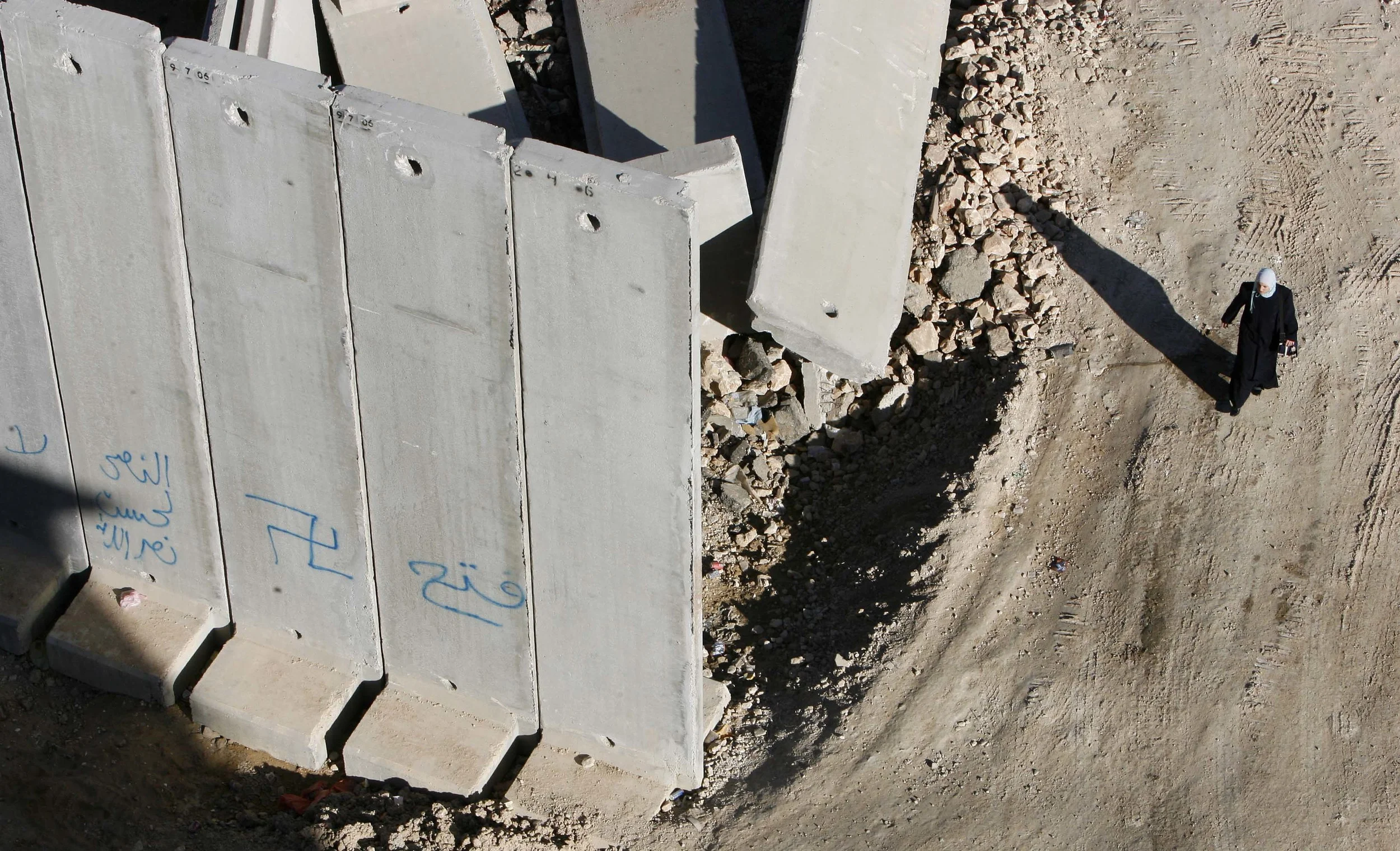 One of few remaining gaps in the Israeli built security wall around Jerusalem. Here at Dahiyat Al-Bareed, a woman walks past sections yet to be installed. November 2006.