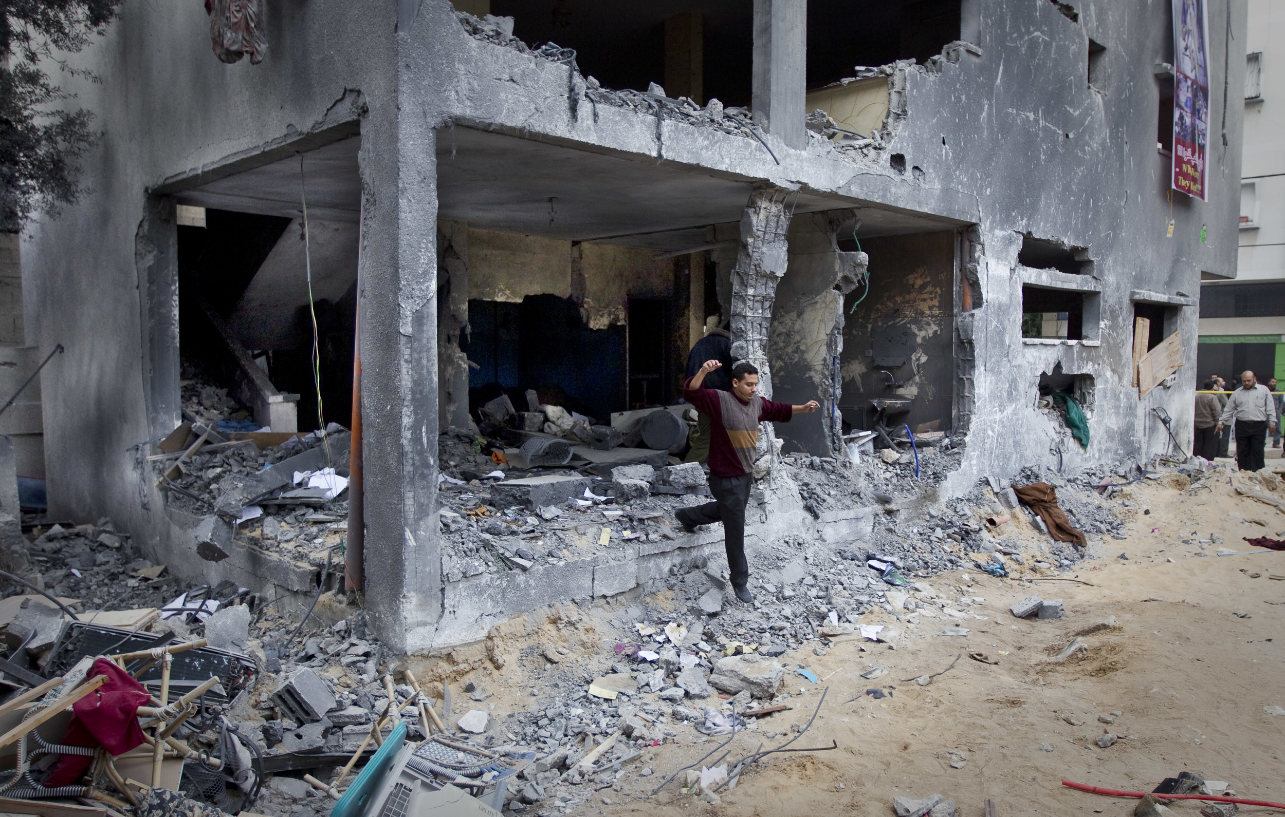  A man jumps from a damaged house next to a property which was destroyed and in which twelve members of one family were killed. Gaza city, December 2012. 