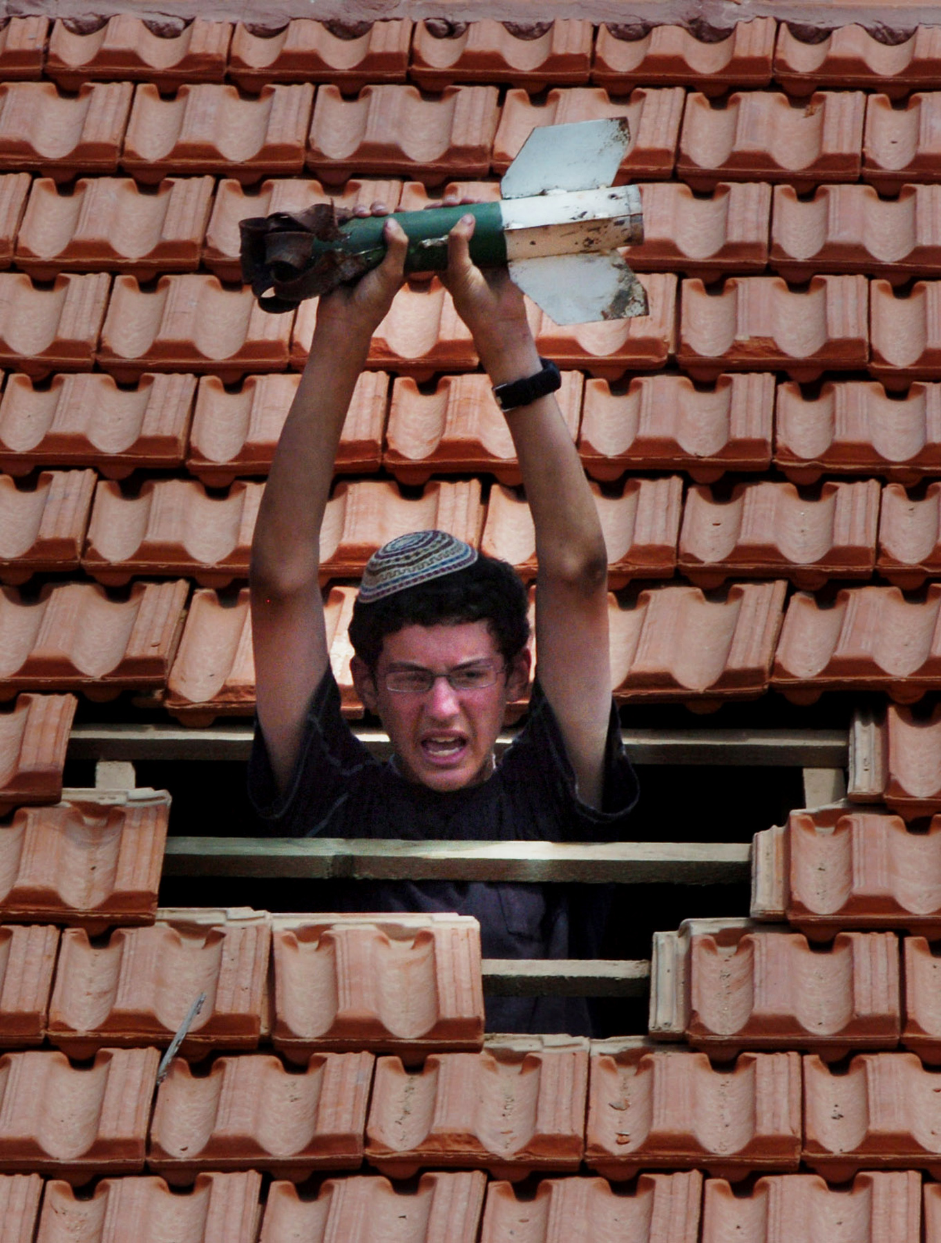  A young settler holds aloft the remains of a Qassam rocket, through the roof of his house that he was forced to leave as part of Israel's disengagement from Gaza. &nbsp;August 2005. 