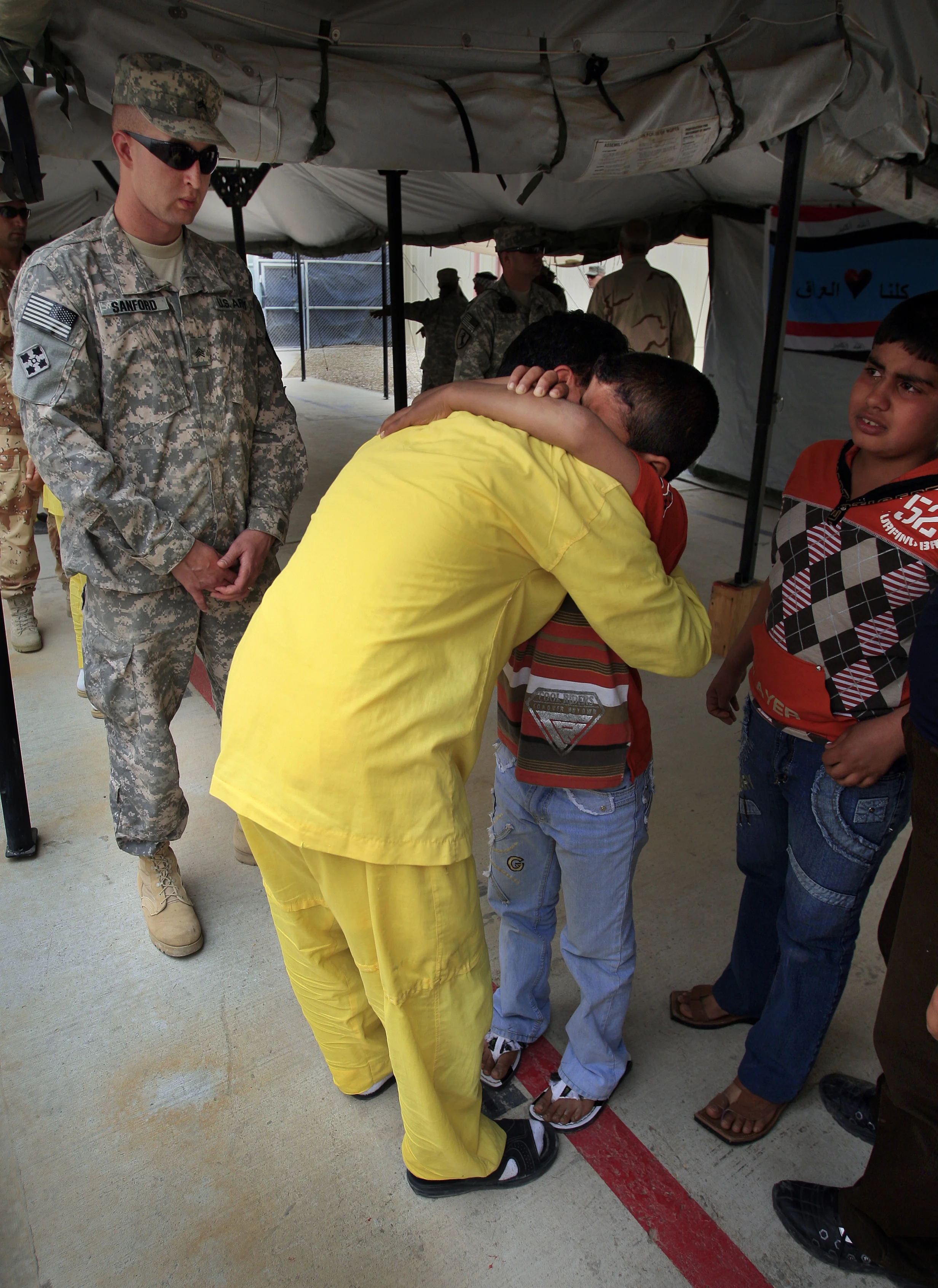 Iraqi detainees at the U.S. run prison, Camp Cropper, are allowed family visits and physical contact, although neither party's feet should cross a red line and are under constant watch by U.S. military guards. (Identities concealed as they are suspects only at this point, not convicts). Baghdad, April 2009.