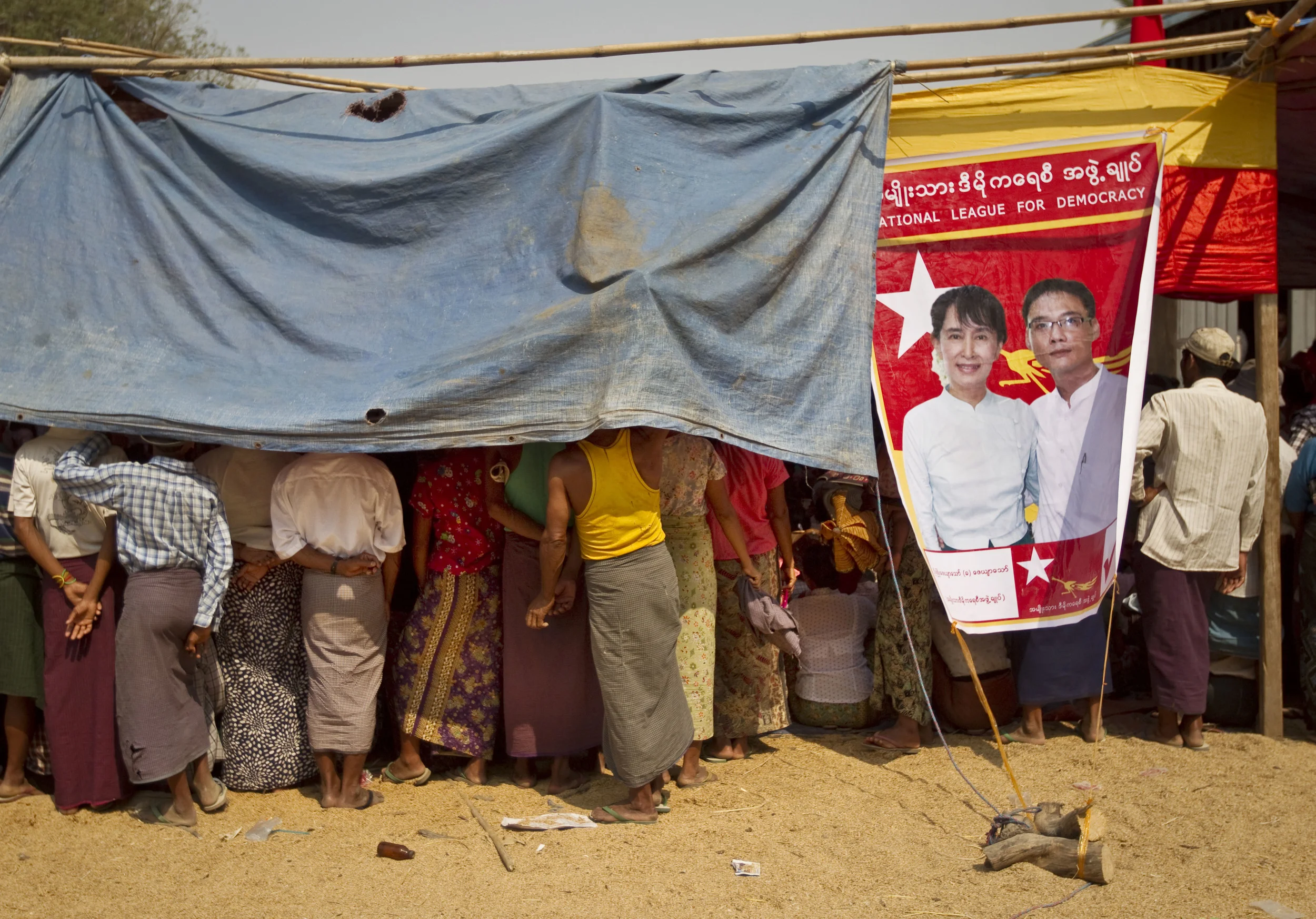  NLD candidate, Aung San Suu Kyi, appears on an election poster to as people gather to listen to a local election rally near to Naypidaw, Burma's capital. March 2012. 