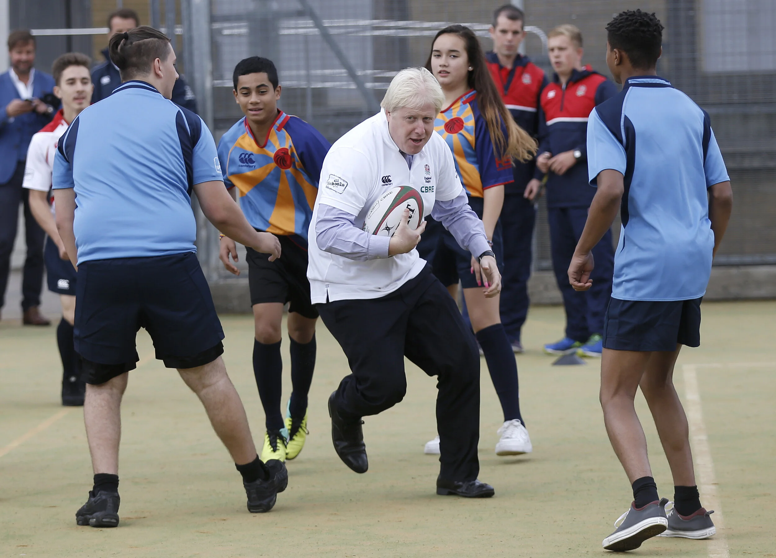  London Mayor Boris Johnson runs with the ball during a rugby coaching session at Haverstock School in London, Britain September 18, 2015 