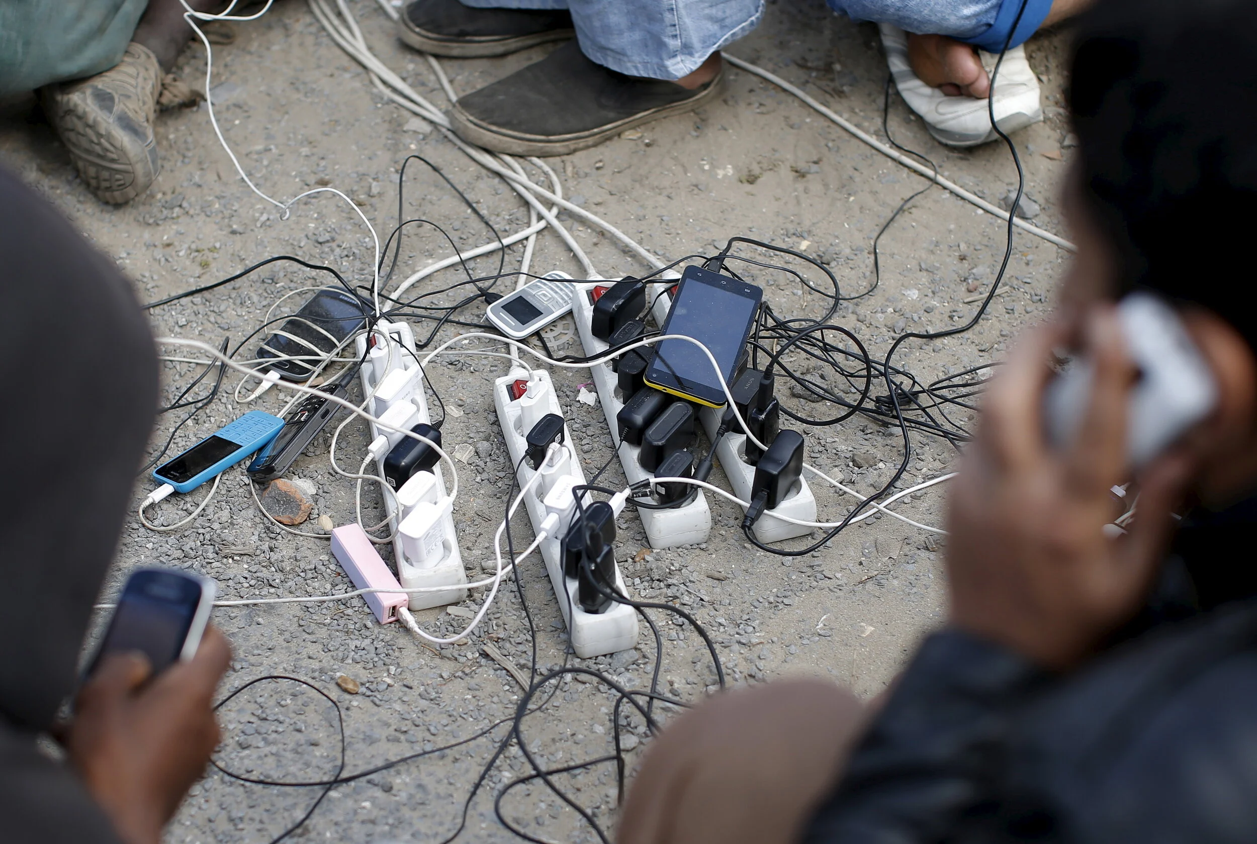  Migrants from Afghanistan charge their mobile phones, powered by a generator, at "The New Jungle" camp in Calais, France, August 4, 2015 