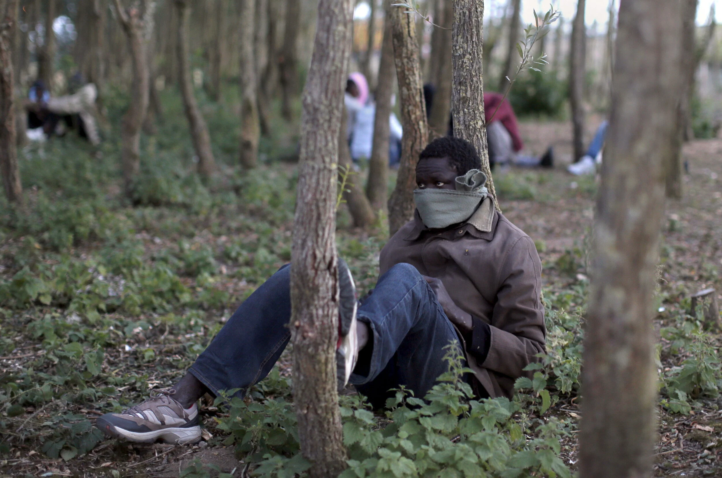  A migrant sits under trees near to the Eurotunnel site in Calais, France, August 4, 2015 