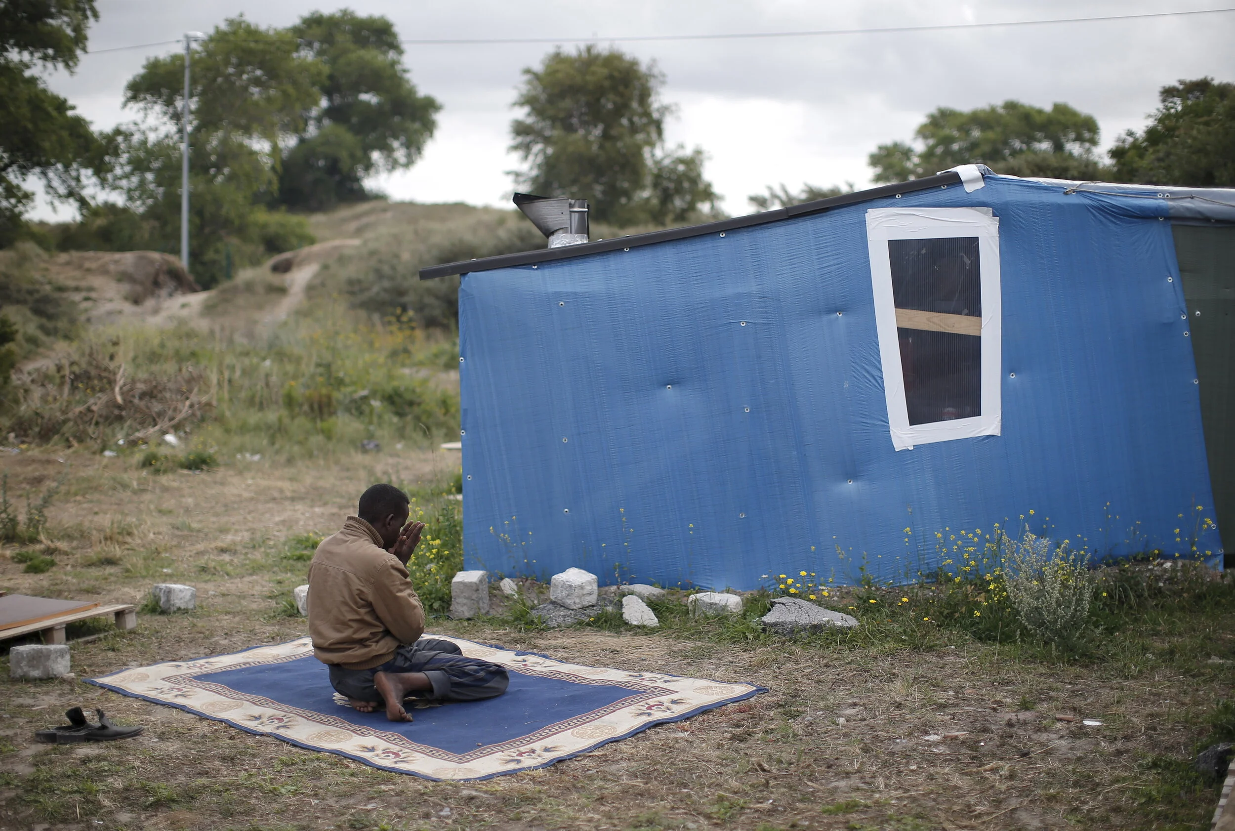  A migrant prays next to his temporary shelter at "The New Jungle" in Calais, France, August 6, 2015 