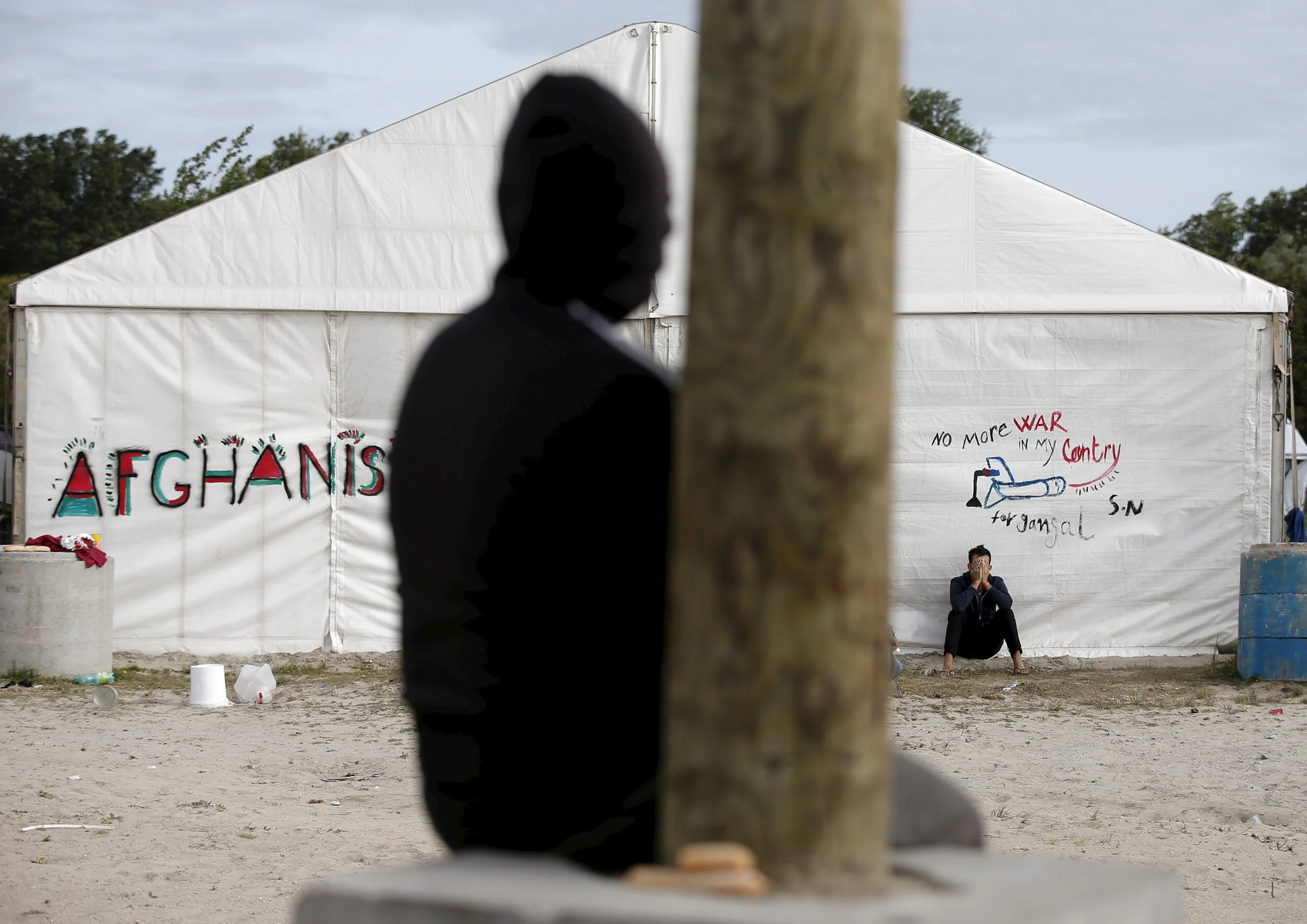  A migrant sits by temporary shelters at "The New Jungle" in Calais, France, August 6, 2015 