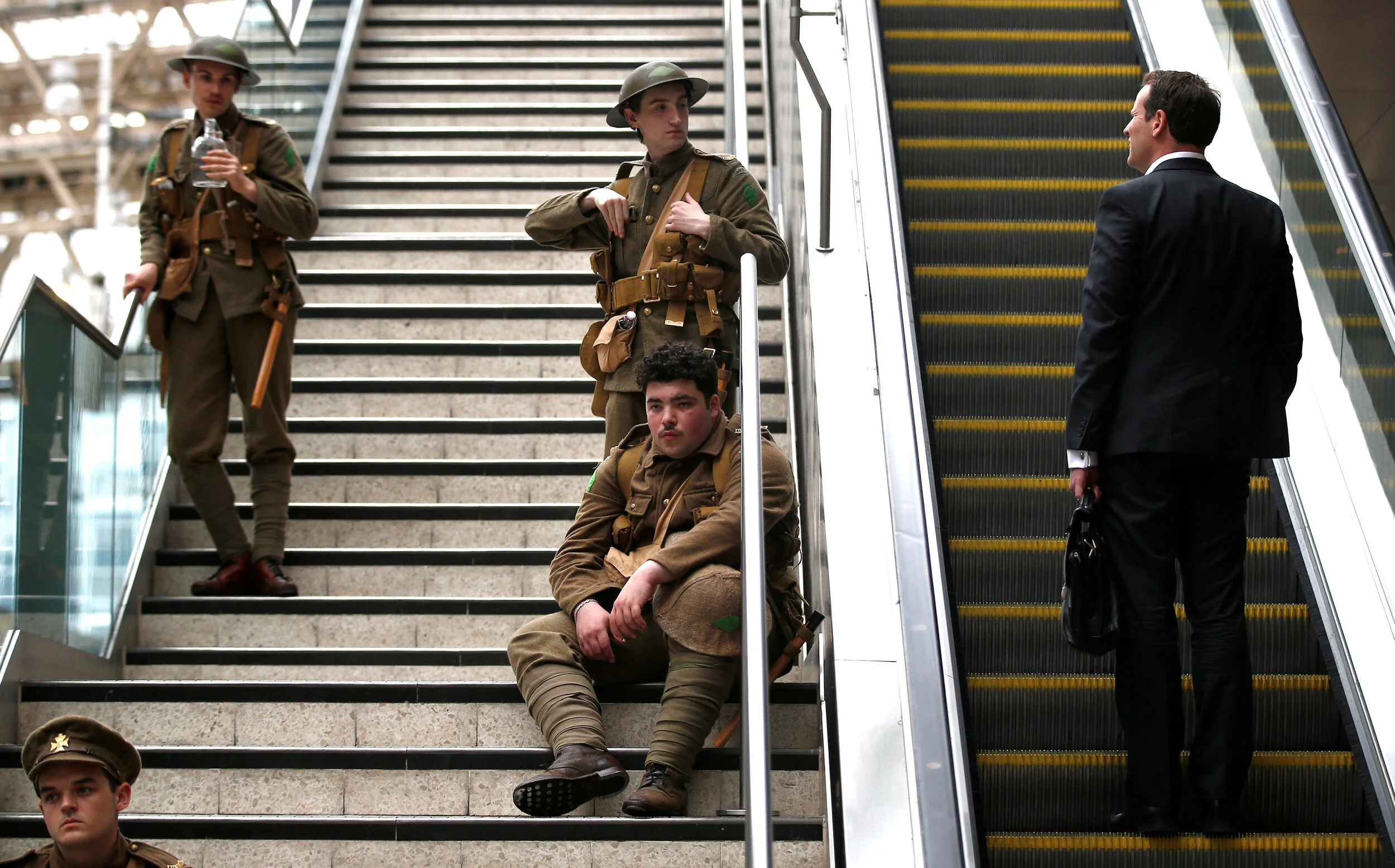  A commuter rides an escalator past volunteer actors dressed in World War I army fatigues, in Waterloo station, to commemorate the start of the Battle of The Somme, in London, Britain July 1, 2016. 