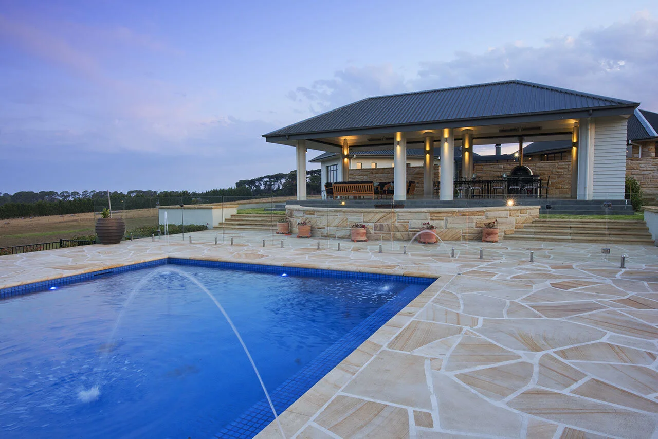 Random square rock faced sandstone cladding, capping and crazy paving pool surround, light-medium brown colour range