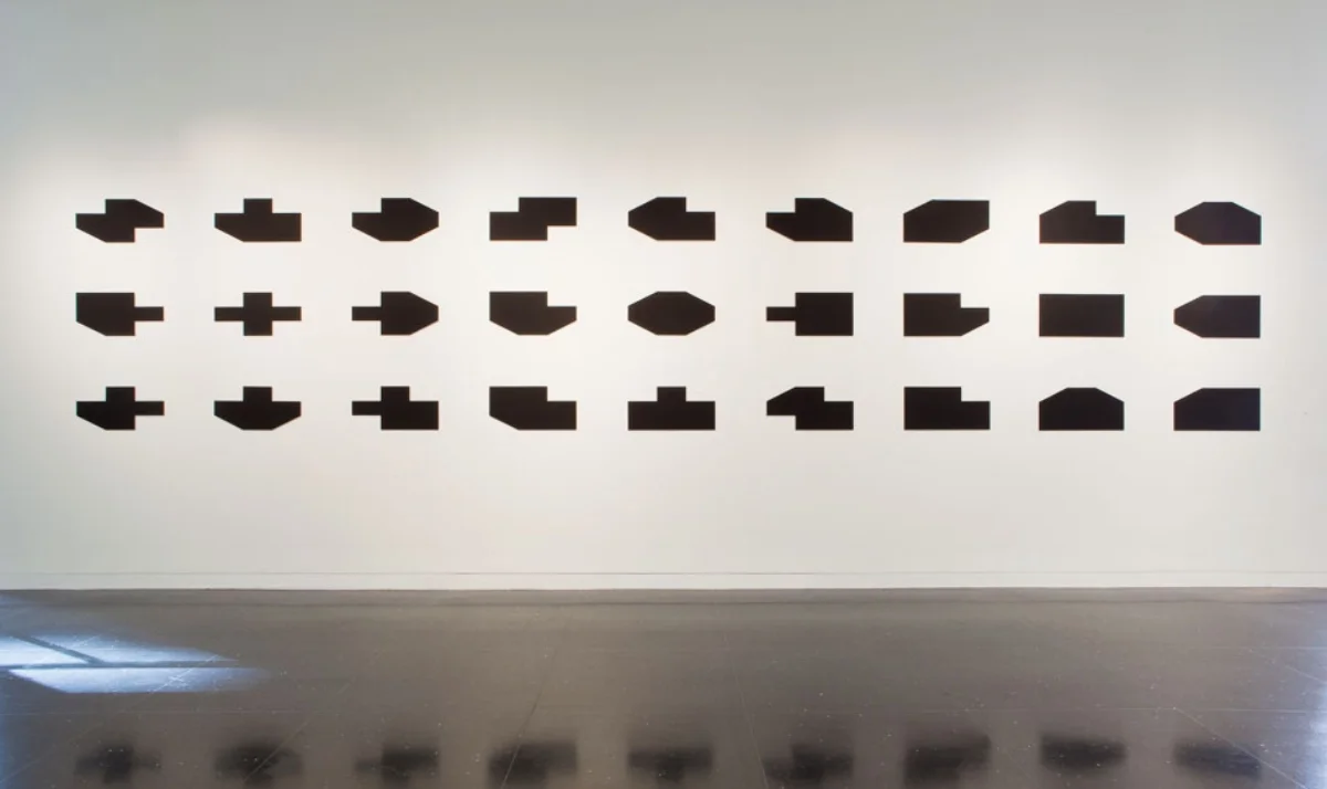 Object into Symbol , 1999 – 2012, paint on 27 aluminum panels, 5.33 x 31 ft: each panel 1 x 2 ft. An arrangement of all the shapes between a rectangular and cruciform shape that can be made by adding or subtracting corner triangles. This was conceived as a purely aesthetic object but has the curious mathematical property that every significant numerical relationship in it can be expressed by the term (3 to x power + 3 to y power). This discovery will result in minor adjustments to future installations. In 2012 show "Figures and Grounds" at The Arts Club of Chicago, guest curator Anne Rorimer.