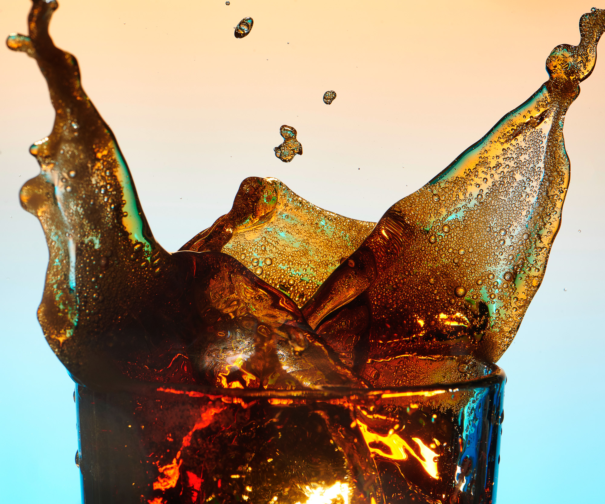 Abstract of ice cube dropping in to a glass of cola soda pop