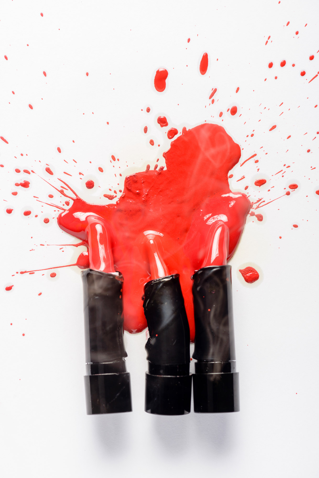 Melted red lipstick making a splash on white background