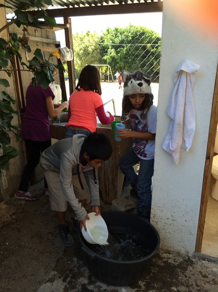 Three 4th graders (my students) and one 5th grader filling the BIG water bucket.