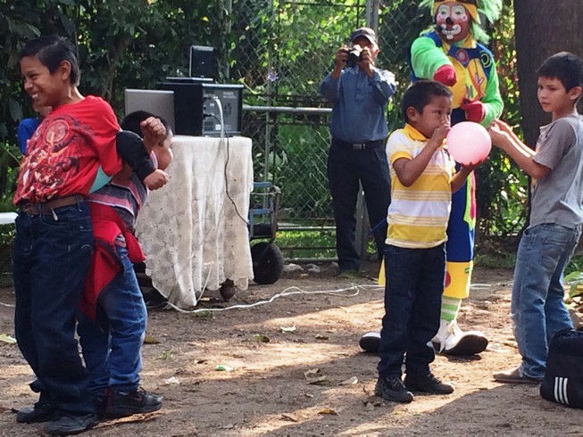 The boys had to do all sorts of funny things with balloons. They were in pairs trying to pop them with their fronts, with their backs, by sitting on them and by asking their moms to sit on them. 