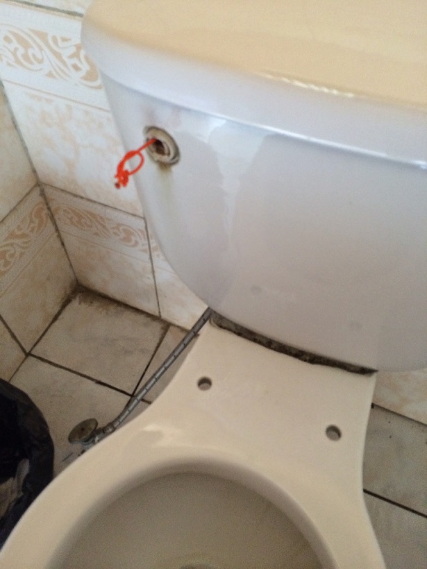 This toilet is missing both a toilet seat and a handle for flushing.