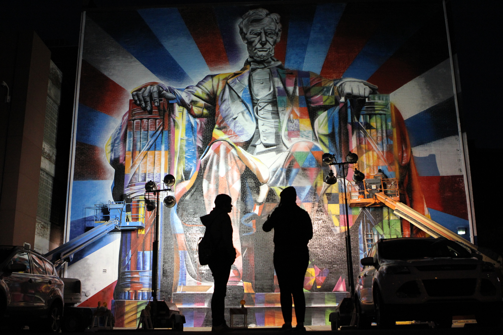  Late into the night Mandee Robinson (right) and Elizabeth O'dell watched Brazilian street-artist Eduardo Kobra and crew put the finishing touches on a mural of Abraham Lincoln on the rear of the Kentucky Theater in Lexington Ky. 