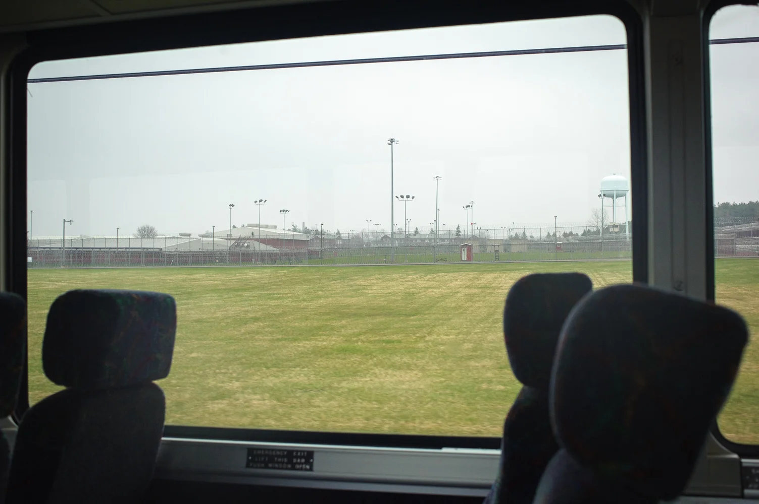 The view of Orleans Correctional Facility from the bus. Like many New York State prisons, it is hundreds of miles from New York City, where many of its prisoners come from. Every Friday and Saturday night hundreds of New Yorkers, mostly women, many with children, undertake 24-hour trips and get on private buses and mini vans to drive all night in order to spend a few hours the next day with their husbands, brothers, mothers and fathers, who have been placed in prisons hundreds of miles from the city. April 26, 2014.