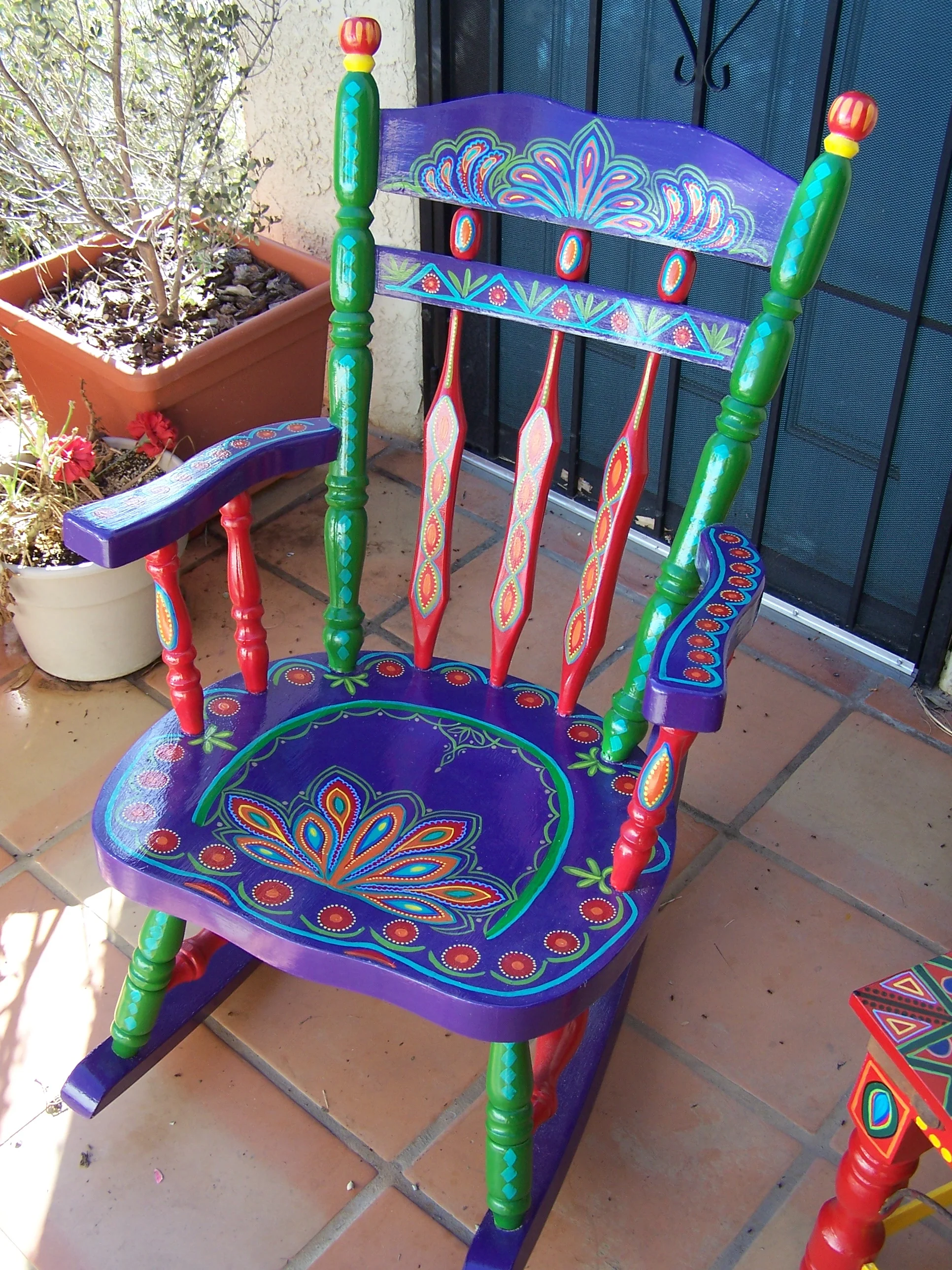  Comfortable old rockng-chair in green, blue, red, and multi-colored design. 
