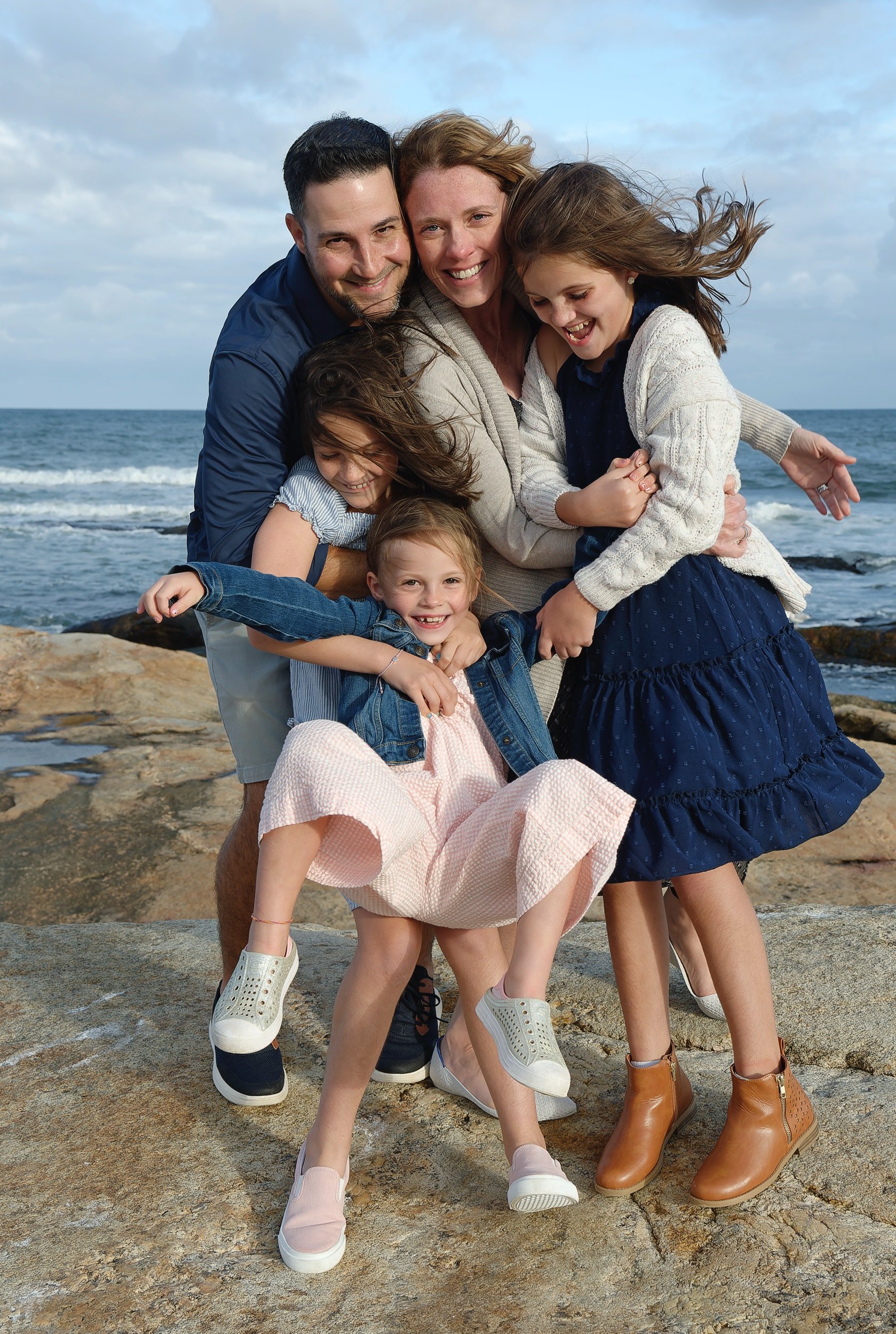 Family of five together on the beach during a coastal portrait session.