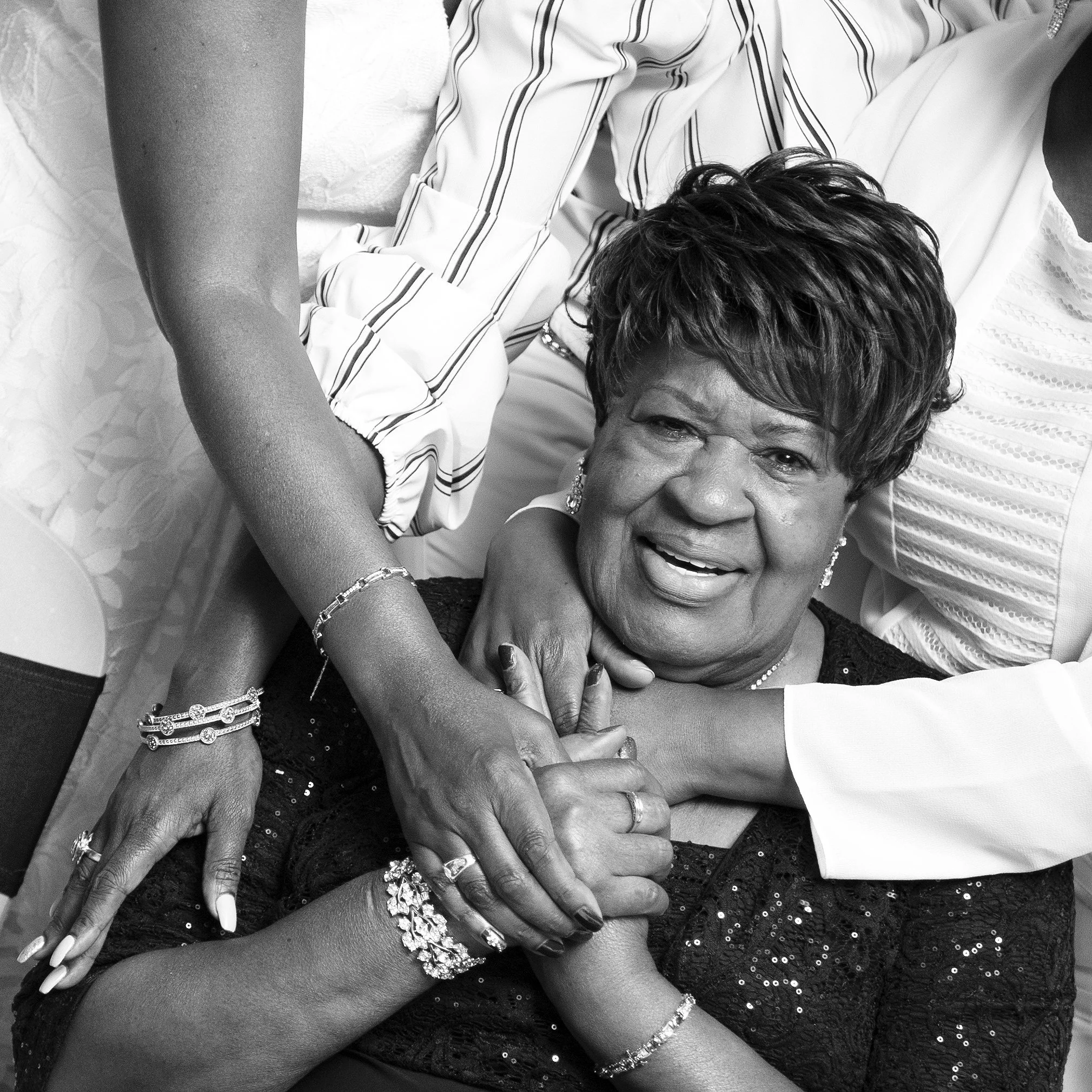 A black and white photograph of Doris' daughters embracing her during her birthday celebration.