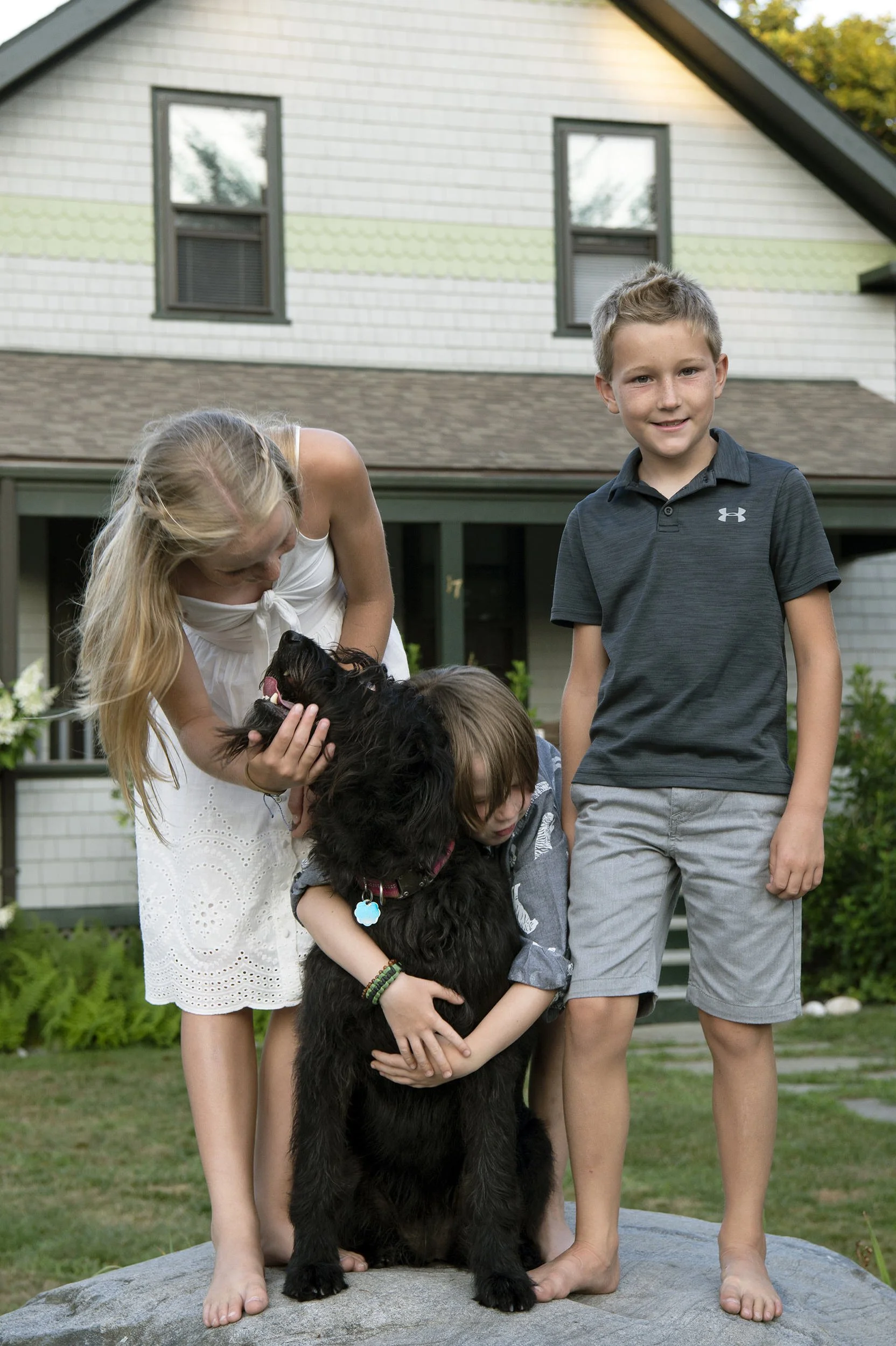 The three little cousins together with the family dog, standing on a rock outside grandma and grandpa's house in Jamestown.