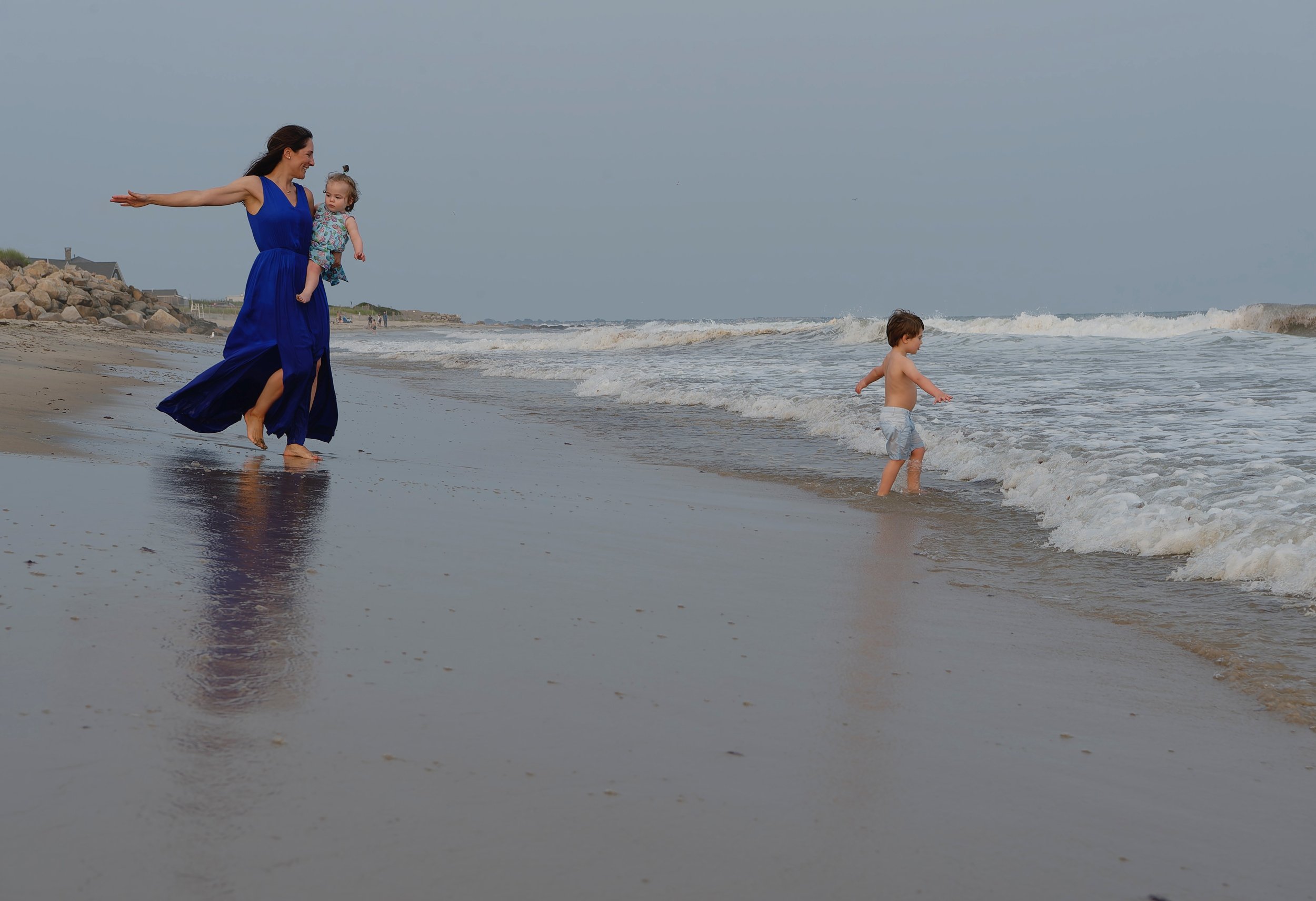 Mom and children playing together along the shoreline.