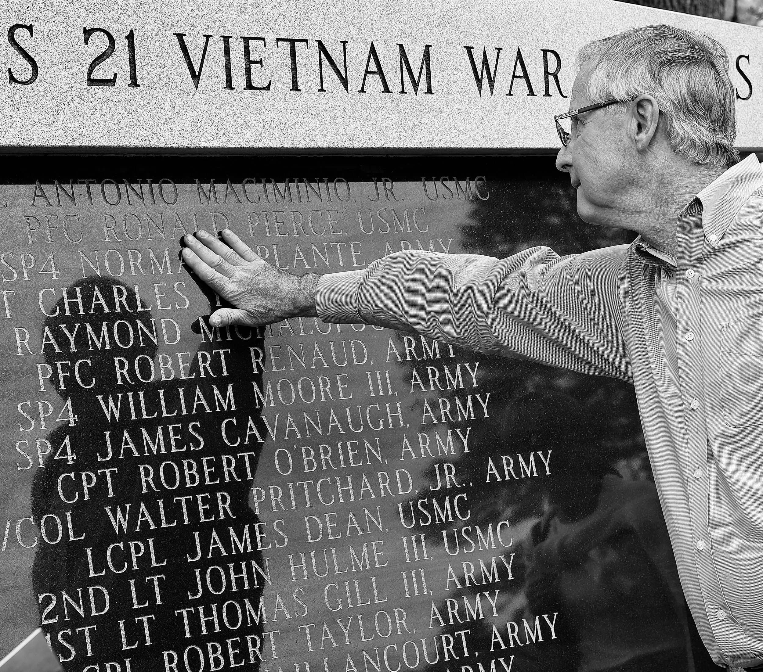 Visitor touching the engraved names on the 21 Heroes Vietnam Veterans Memorial.