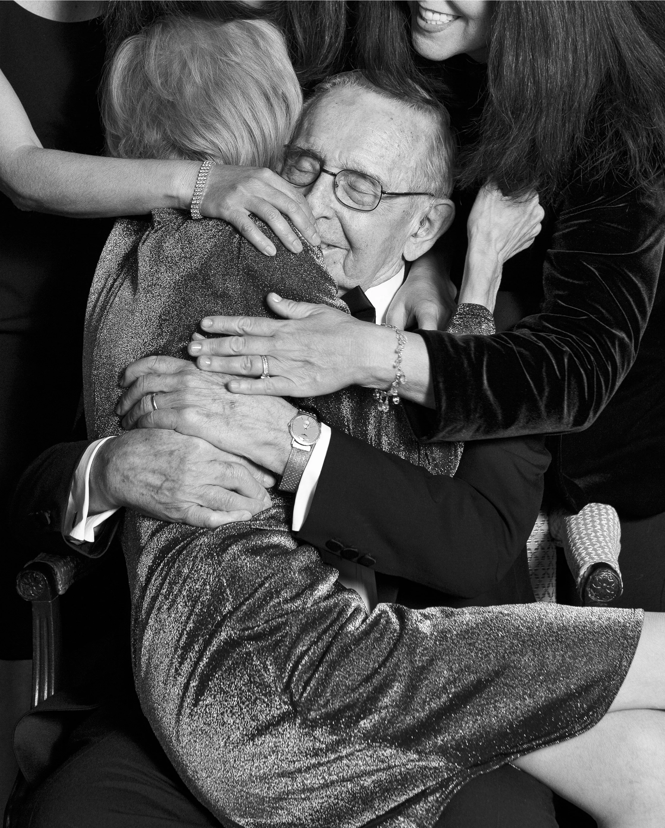 Gladys, Morris, and their adult children embrace celebrating their 60th wedding anniversary.