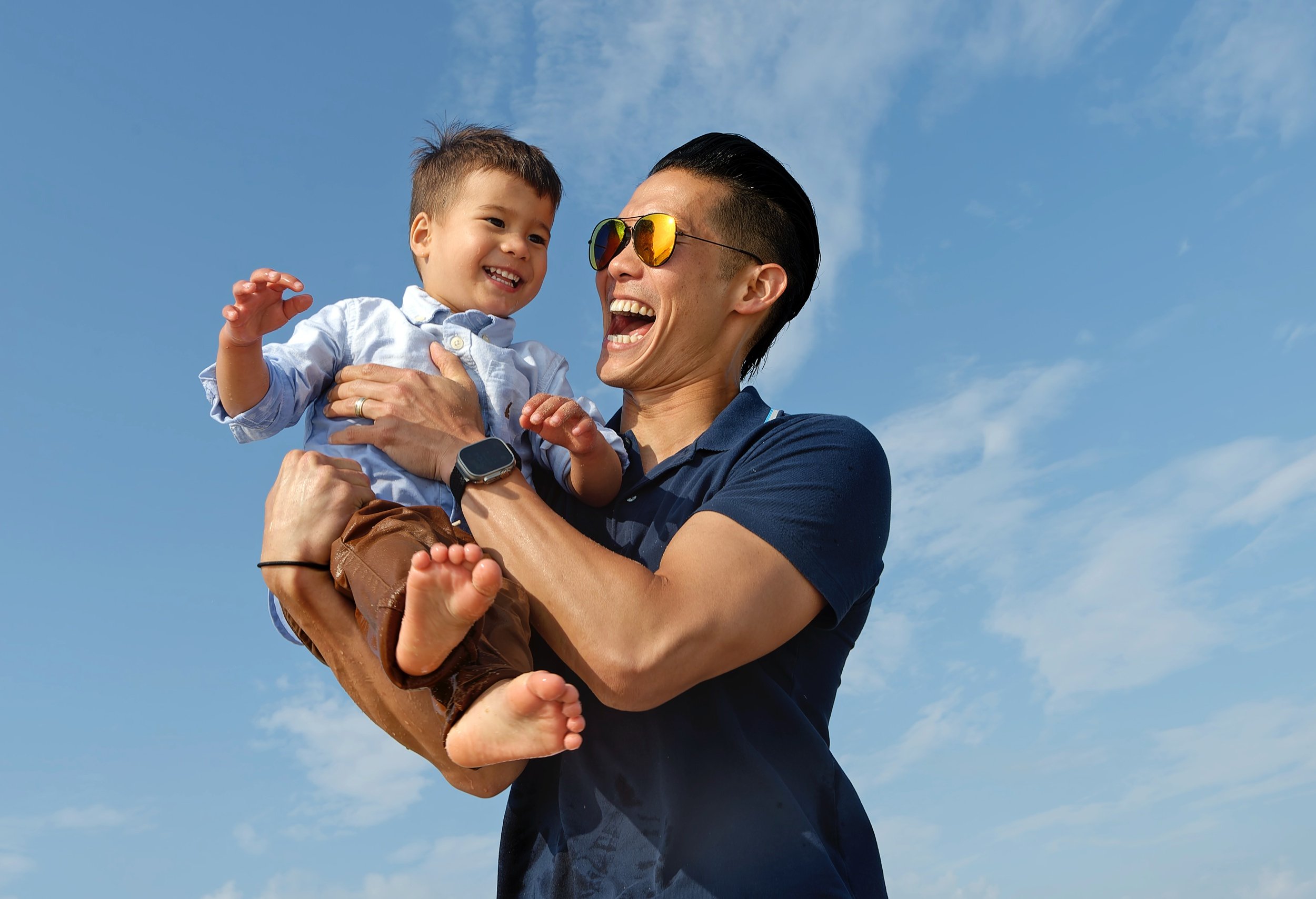 Father holding his young son against the evening sky at South Beach.