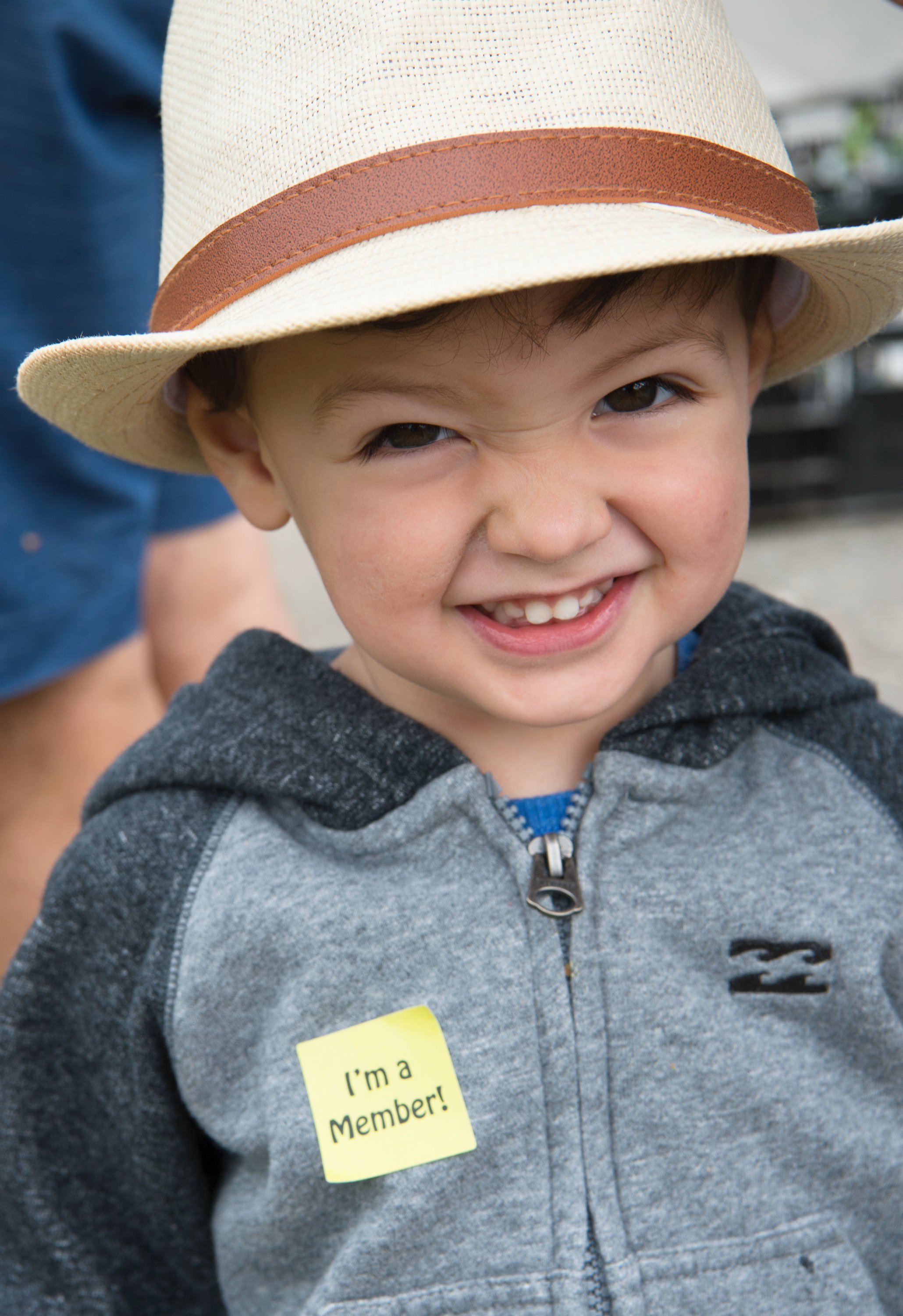 Young visitor wearing a straw hat at the Southside Community Land Trust plant sale.