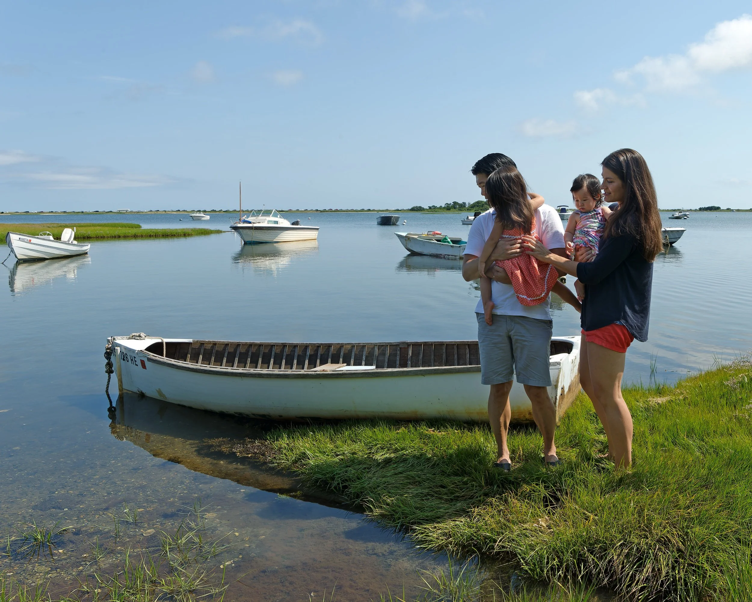 Family standing beside a small boat overlooking the harbor.