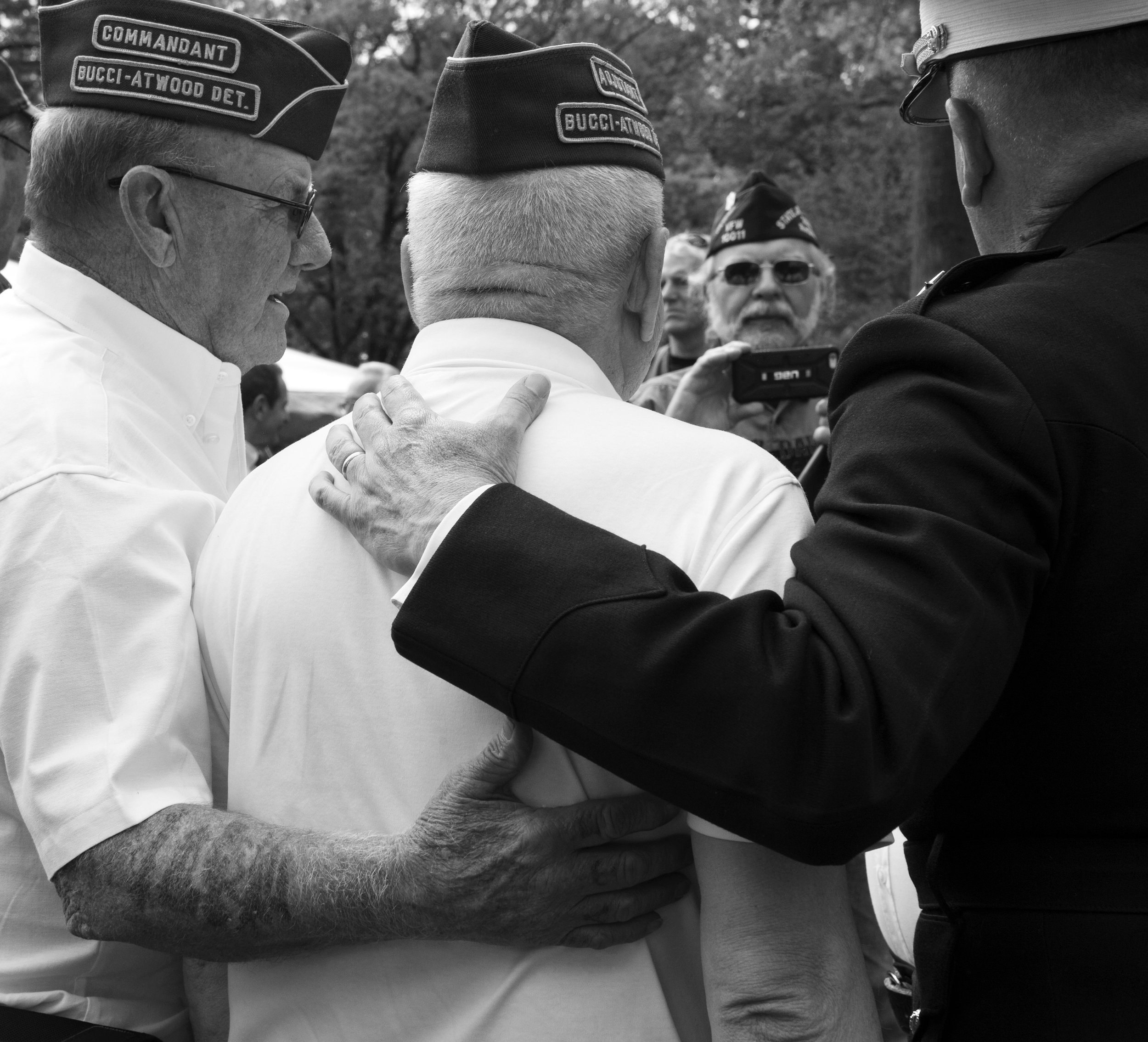 Black and white of veterans embracing during the annual 21 Heroes remembrance ceremony.