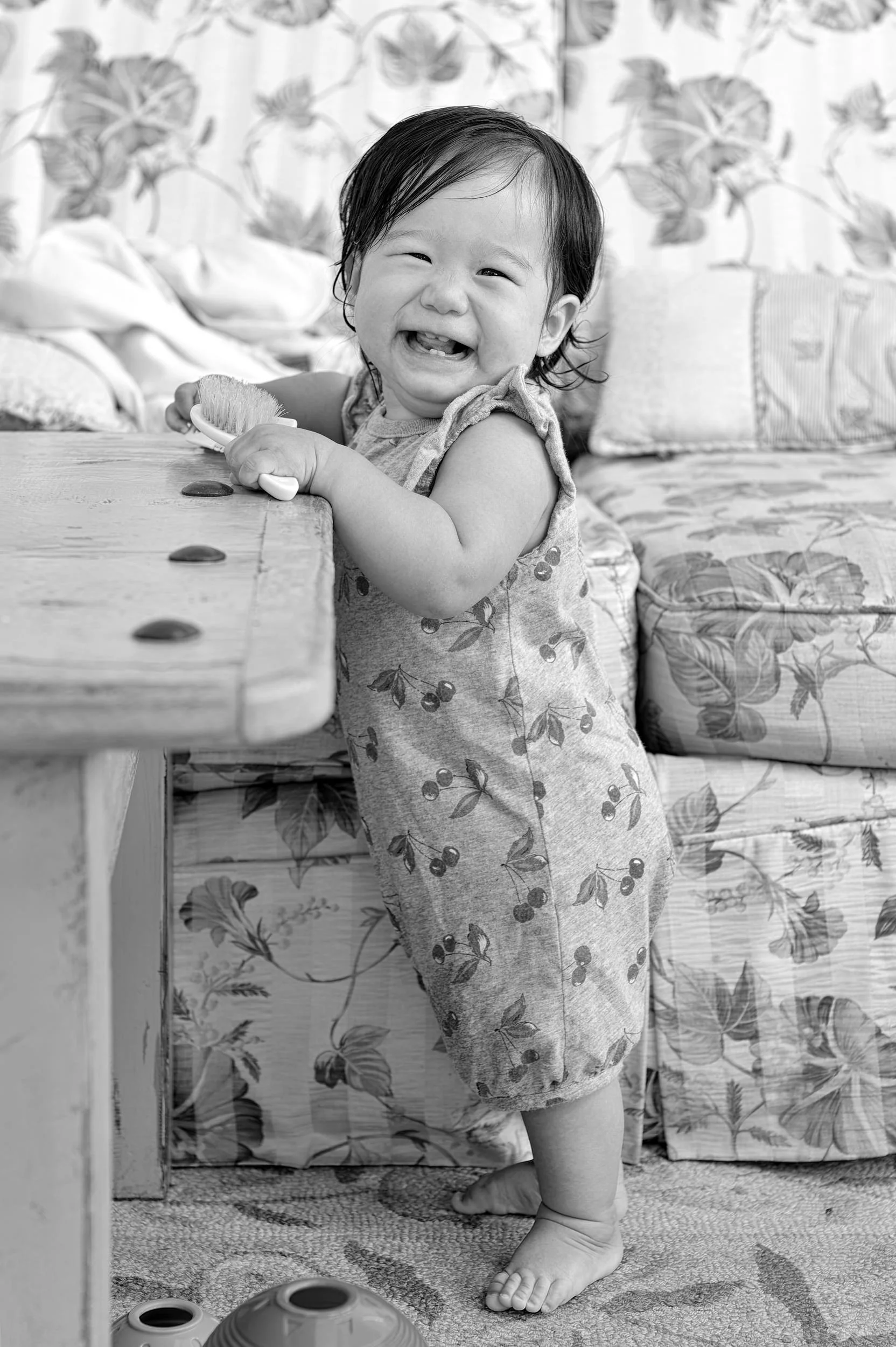 Black and white portrait of a baby taking early steps inside the vacation home.