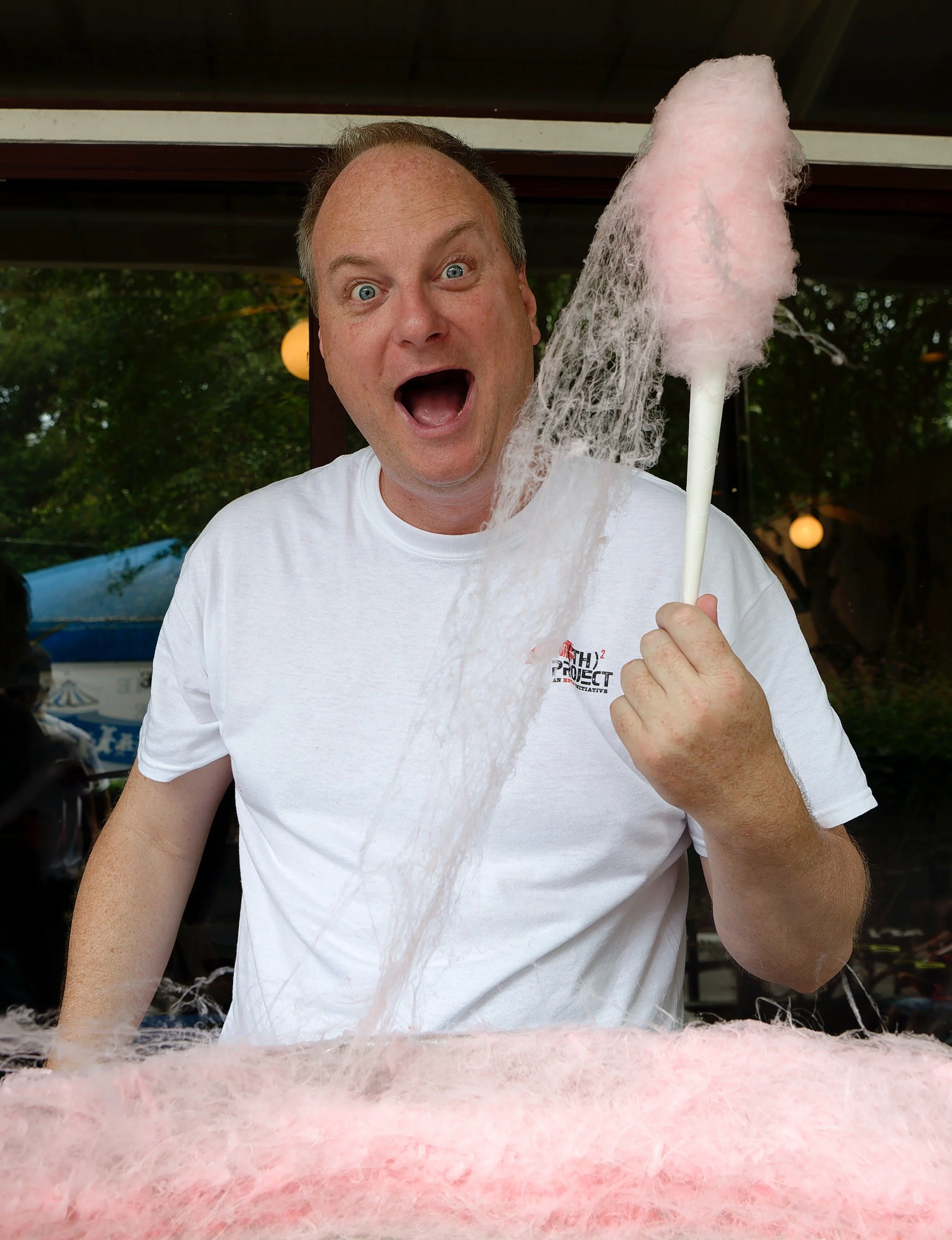 Event Pros Take Action volunteer holding cotton candy during Covenant House's carnival celebration.