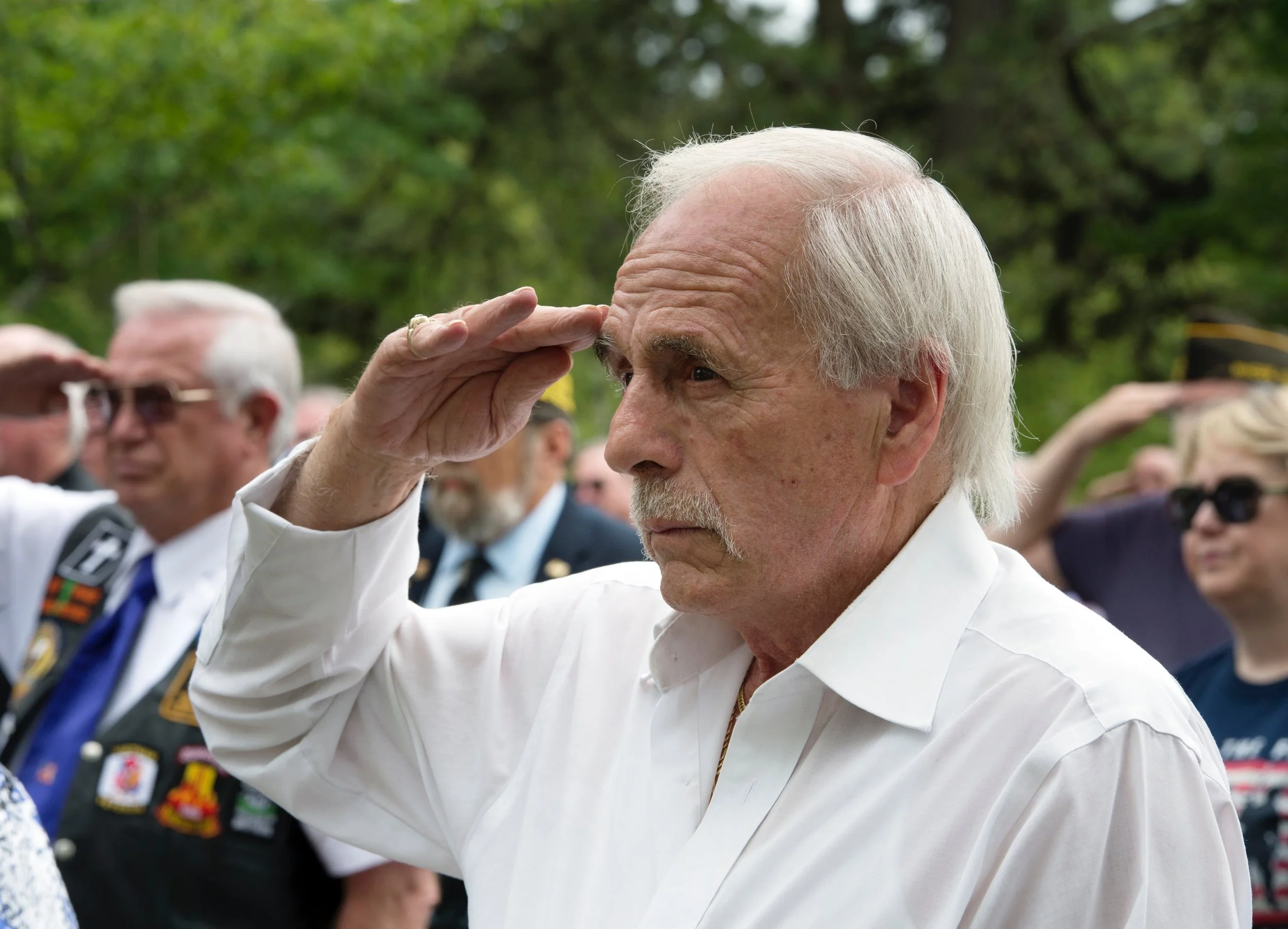 Vietnam veteran saluting during the playing of military honors.