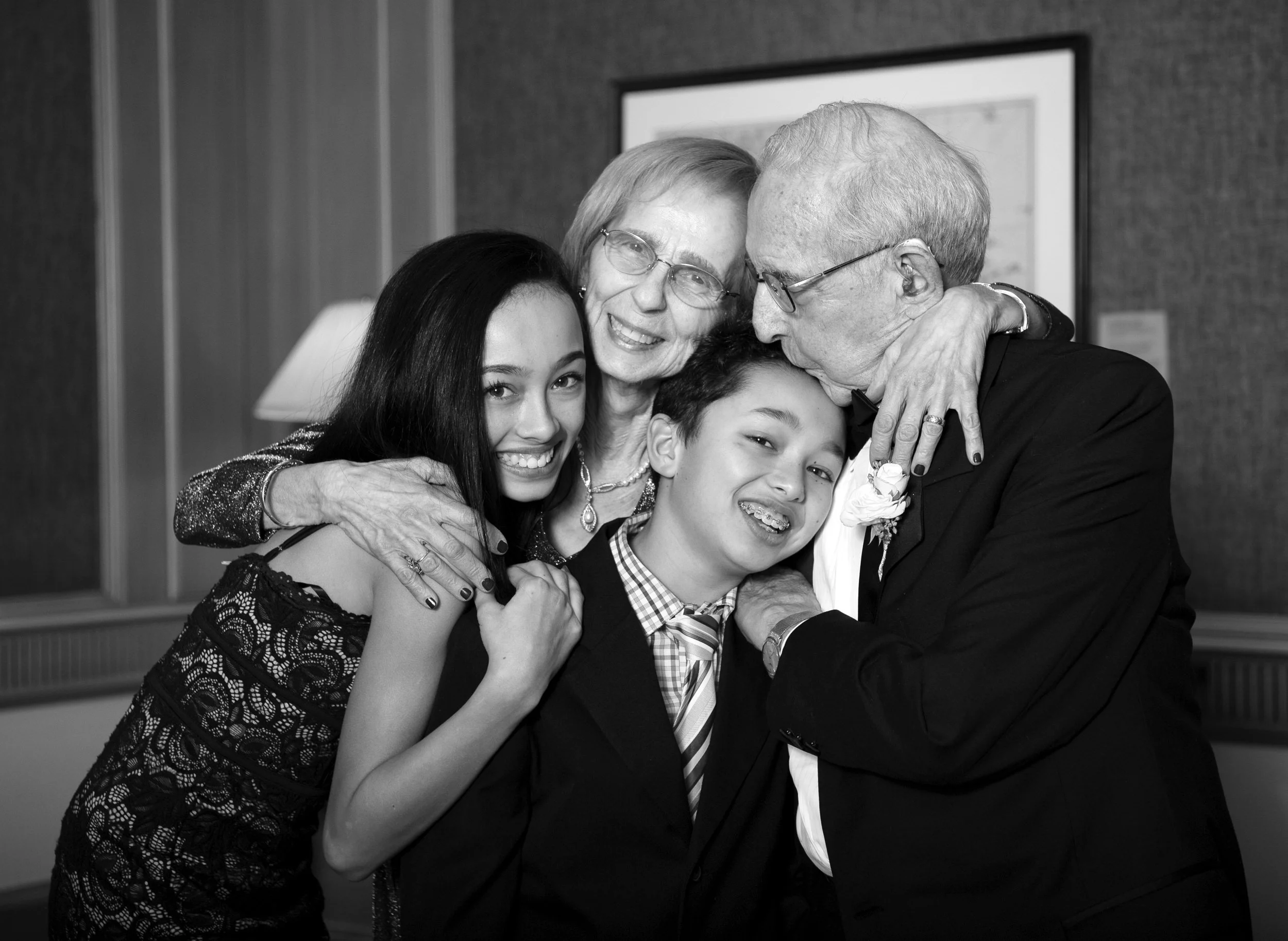 Black and white portrait of Gladys and Morris embracing their grandchildren.