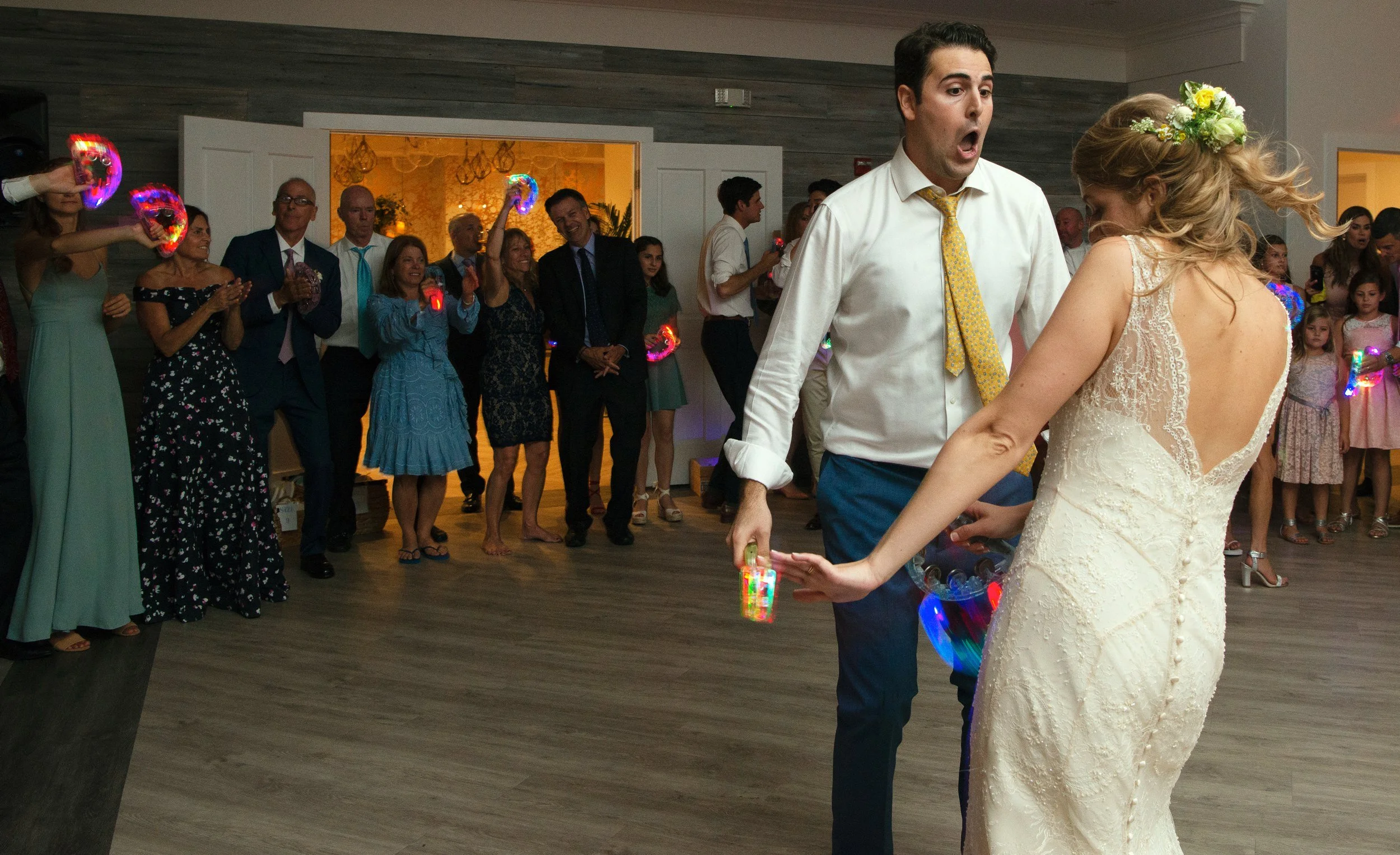 Wedding guests surround the bride and groom dancing at the reception