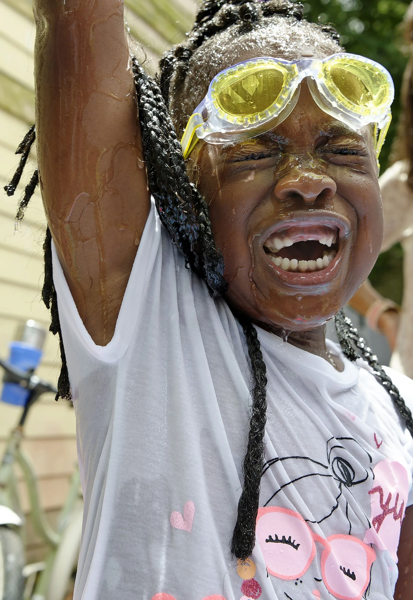 Excited young girl wearing goggles smiles while playing in a children’s pool.